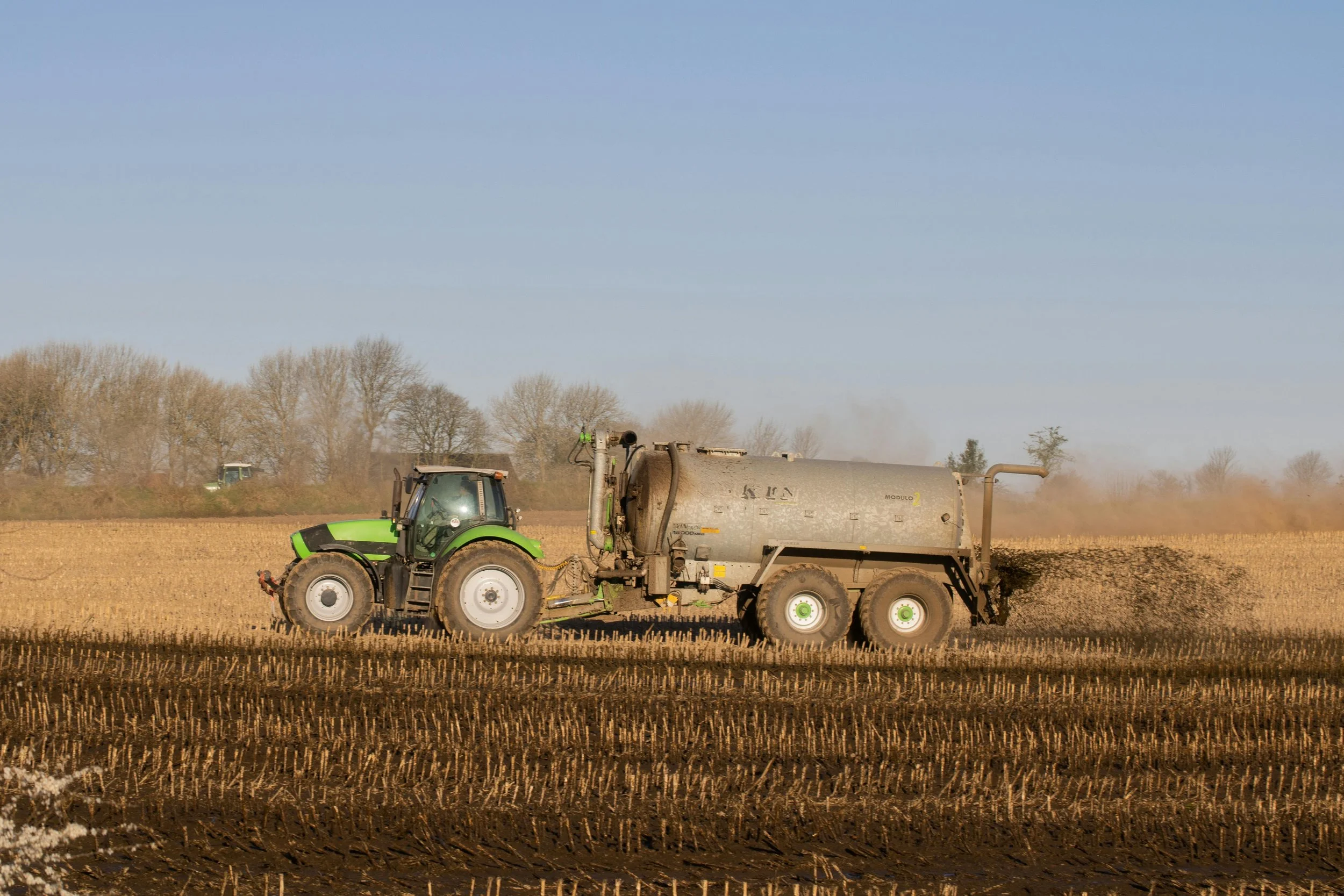 Tractor and tanker spreading digestate on arable farmland in England under NVZ land application rules