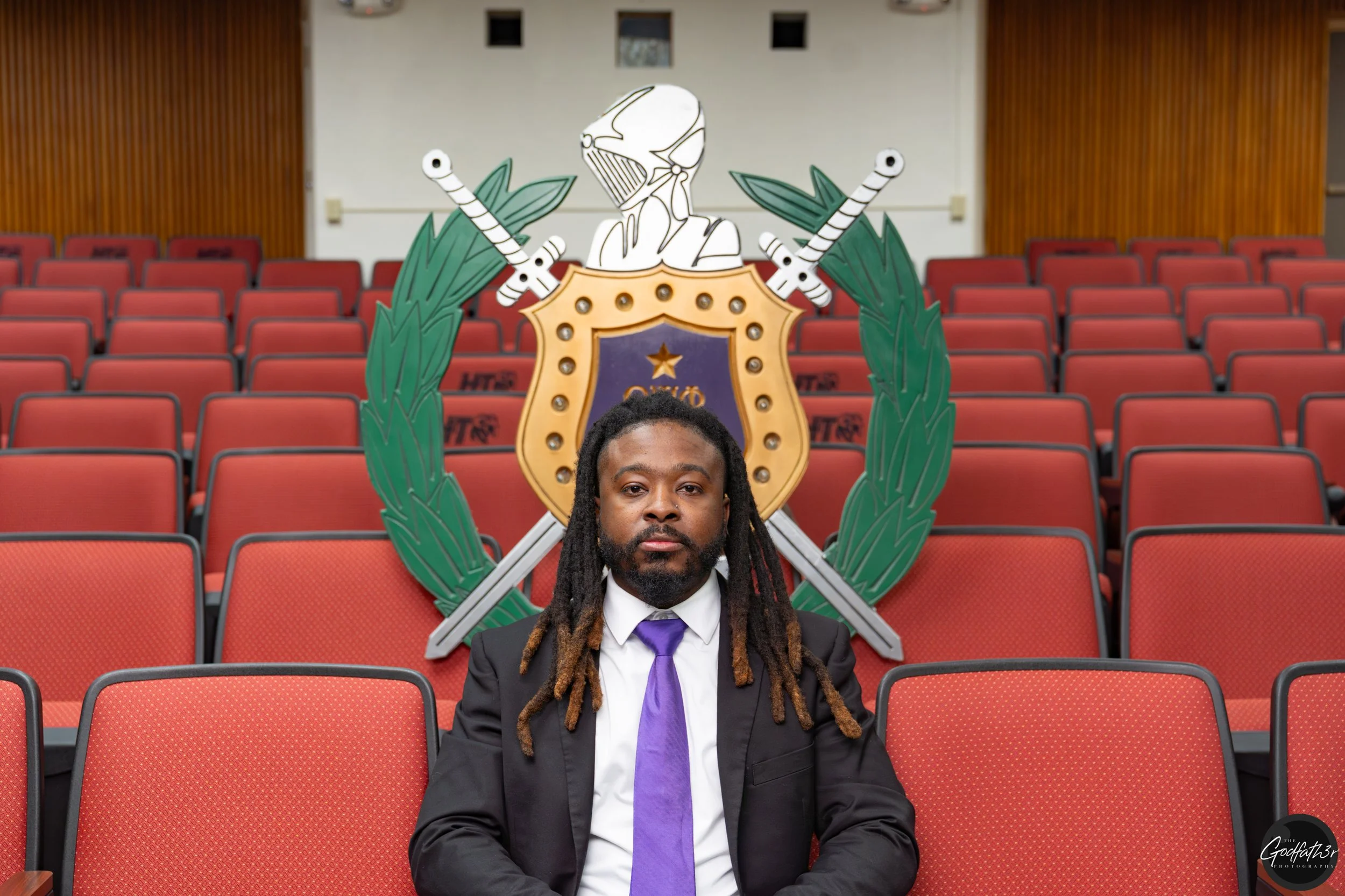 A man in a tuxedo with a polka dot bow tie and glasses, posing for a photo indoors.