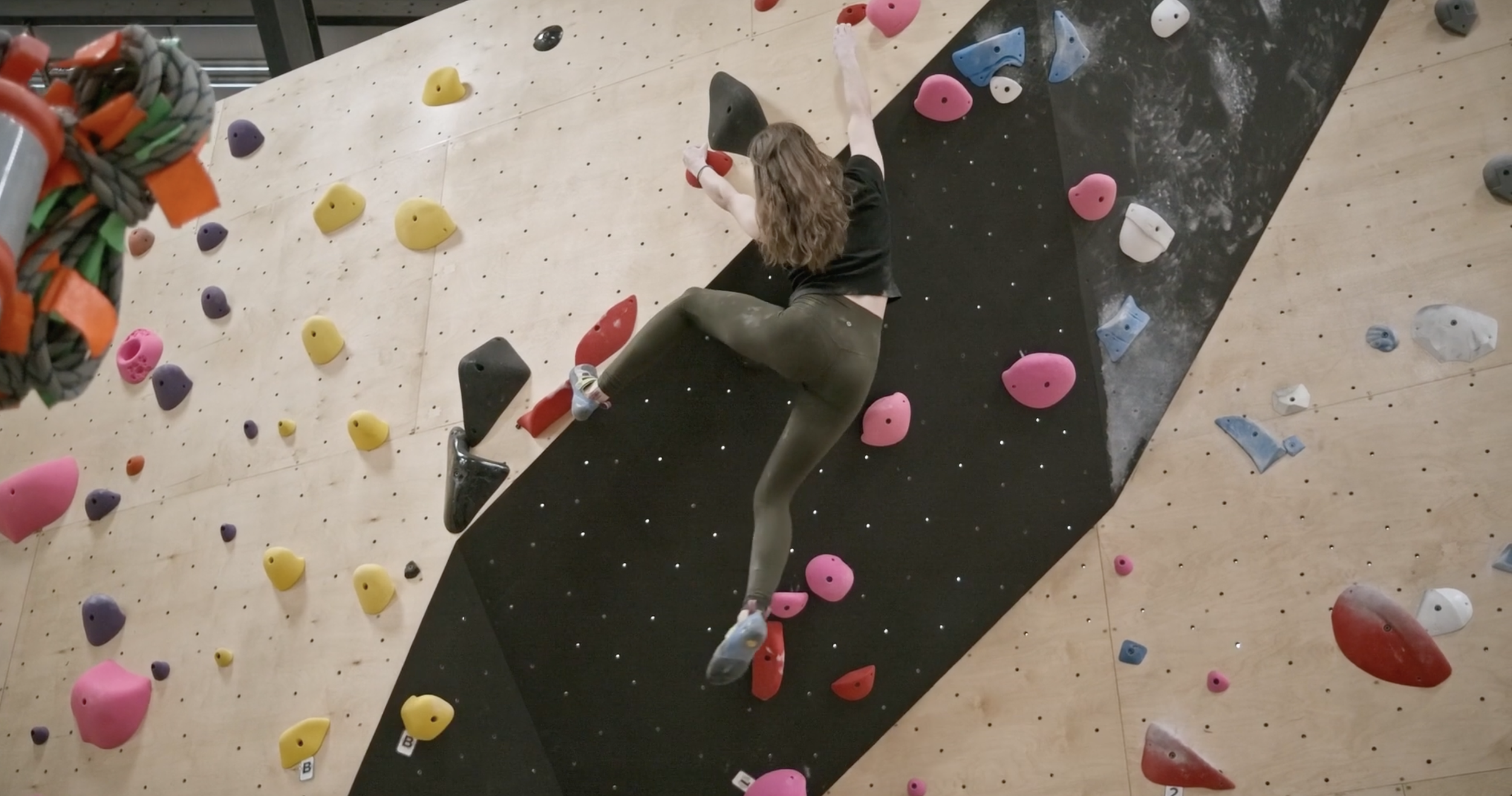 Woman climbing an indoor rock wall with colorful holds