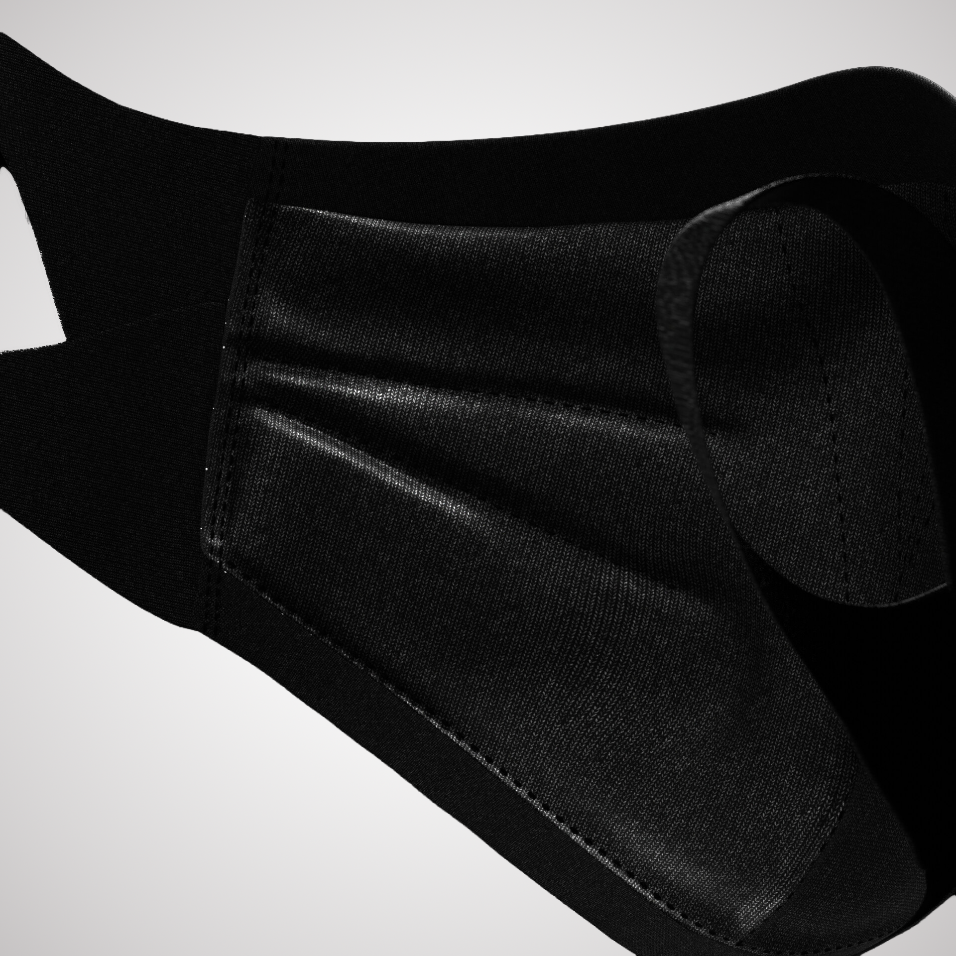 Close-up of a black fabric face mask with adjustable ear straps, displayed against a light background.