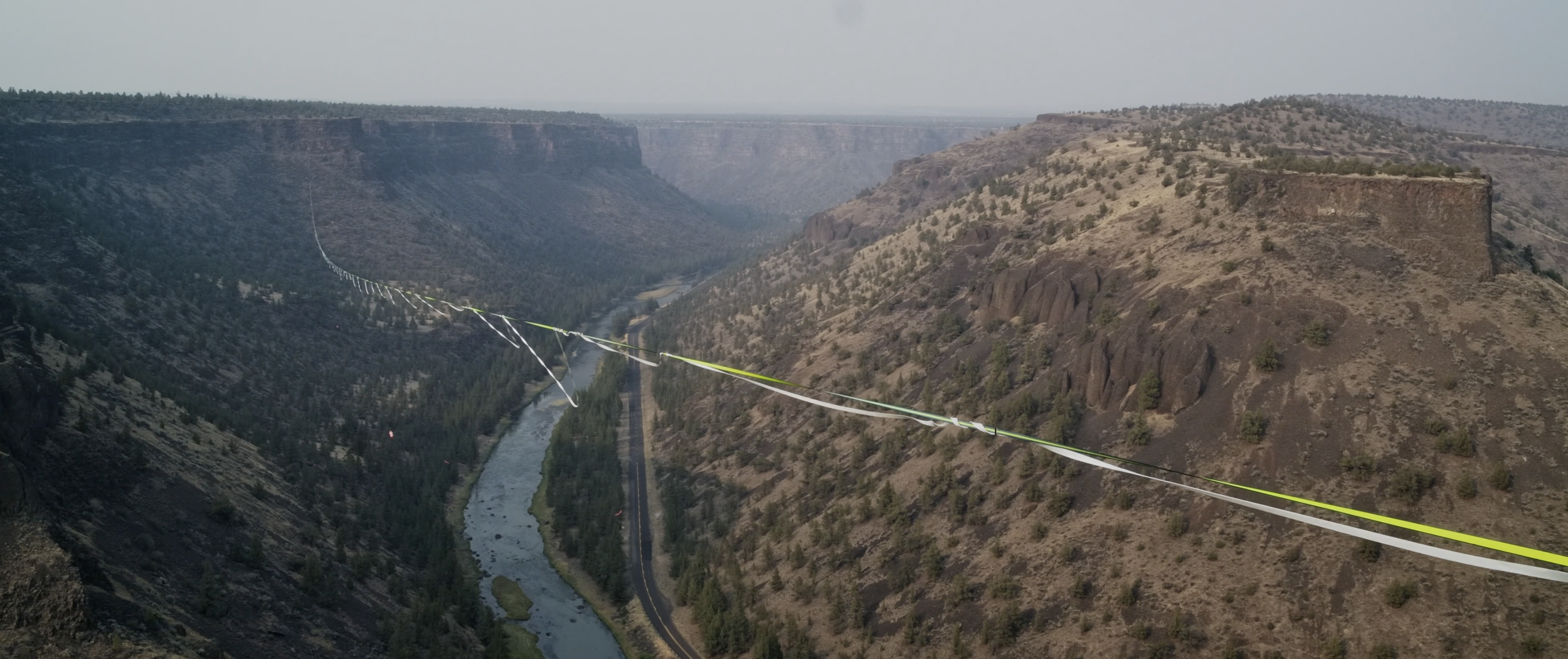 A large canyon with steep rocky walls, a river flowing at the bottom, and a suspension bridge crossing the canyon.