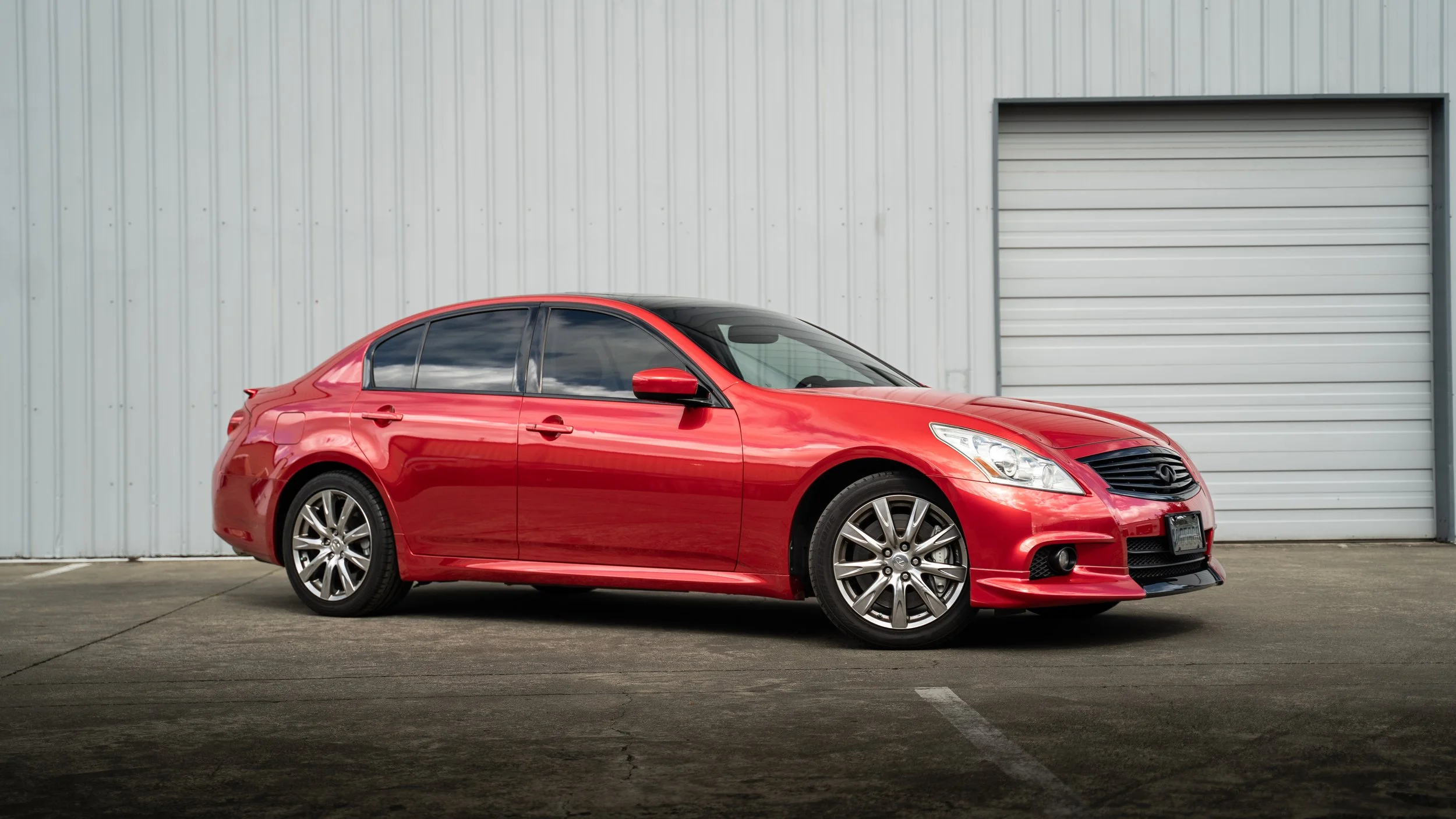 Vampire Red vinyl wrapped Infiniti sedan with freshly installed window tint, photographed outside Tailored Garage in South Hill, Puyallup WA.