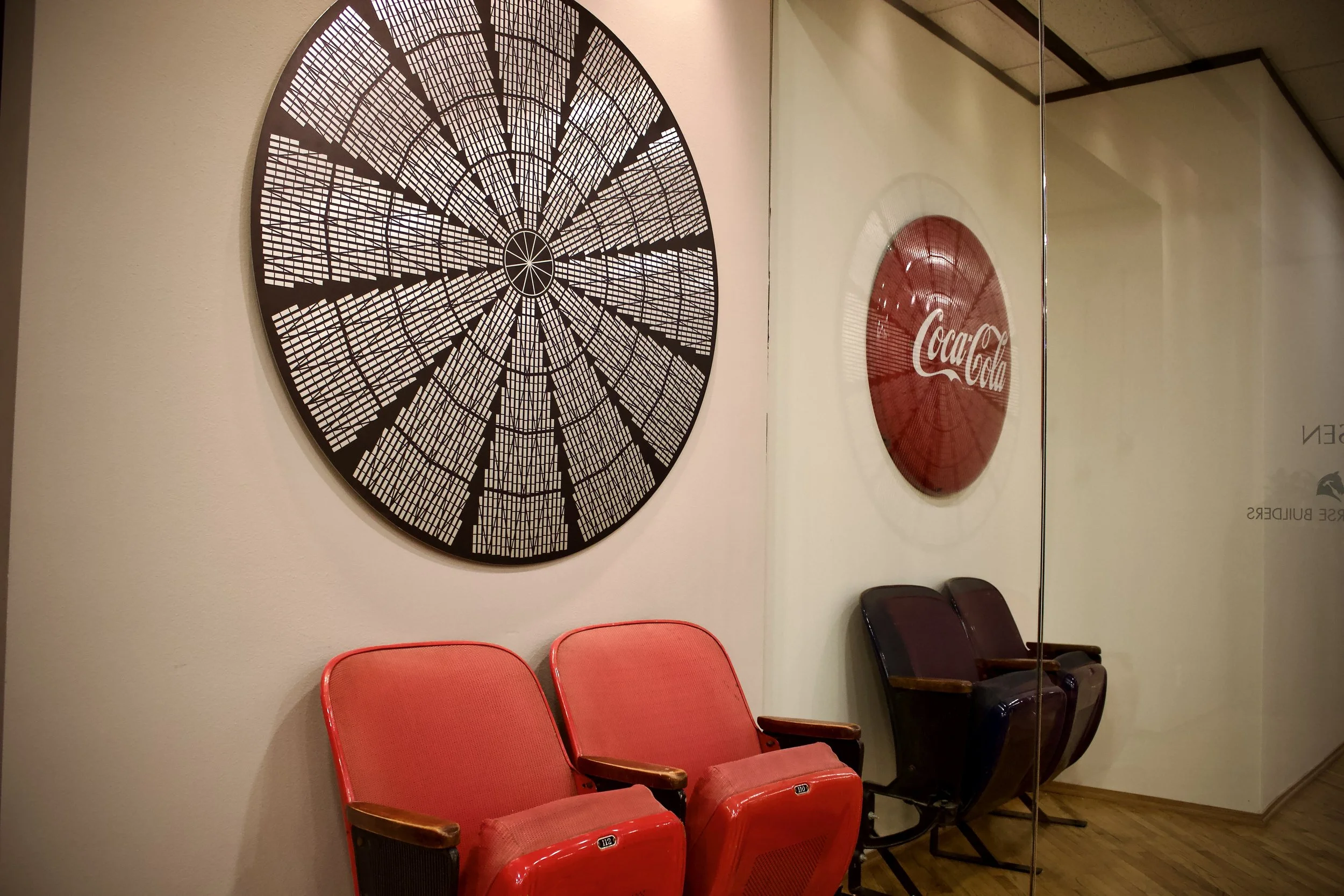 Red and black chairs in front of wall with large laser-cut clock and Coca-Cola sign.