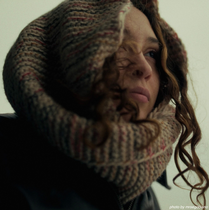 A geometric logo design with curved white lines forming letter 'D' shapes on a brown background.