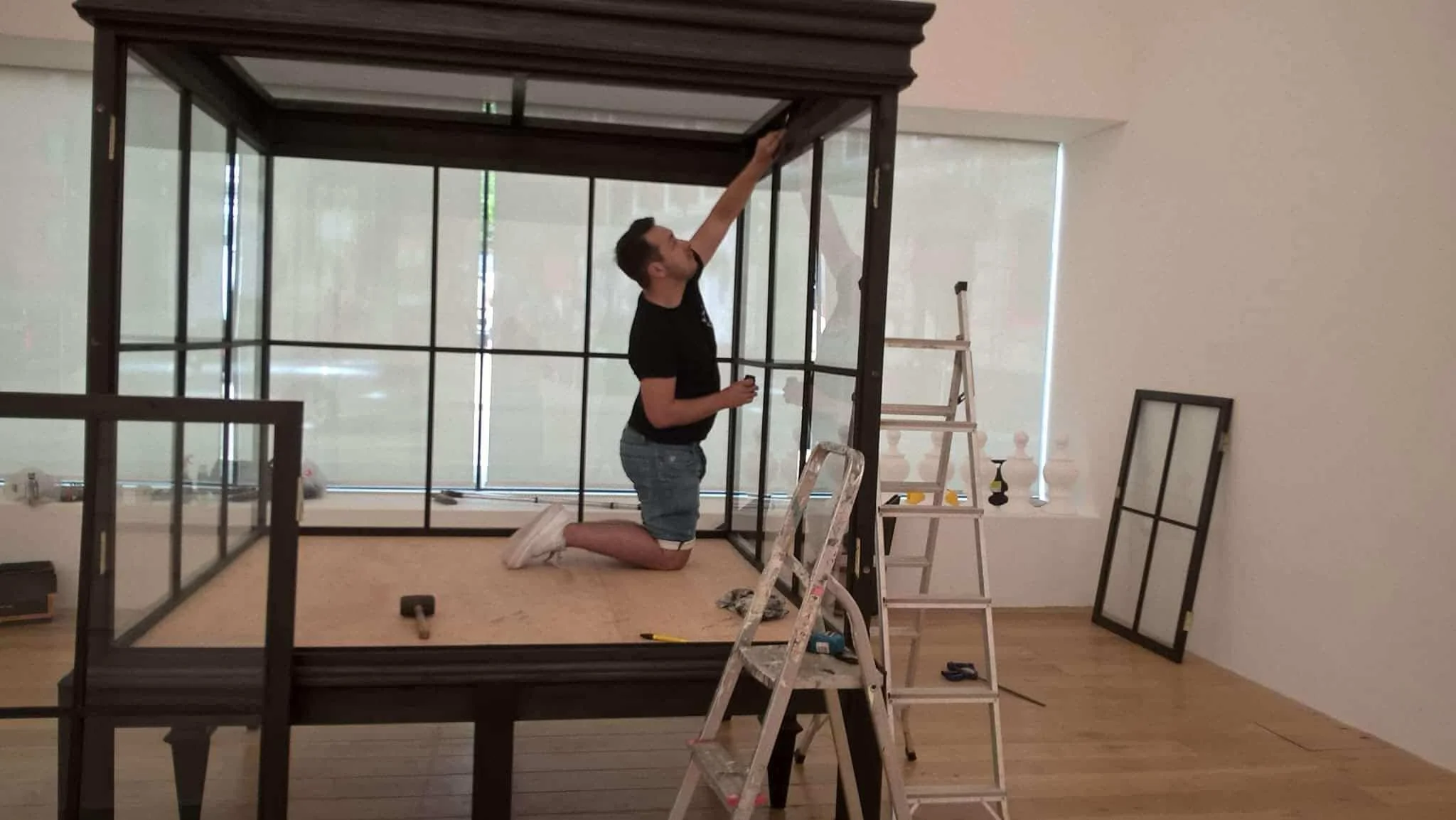 Master craftsman Michael of Foxborough Furniture installing bespoke glass display cabinets for Pablo Bronstein