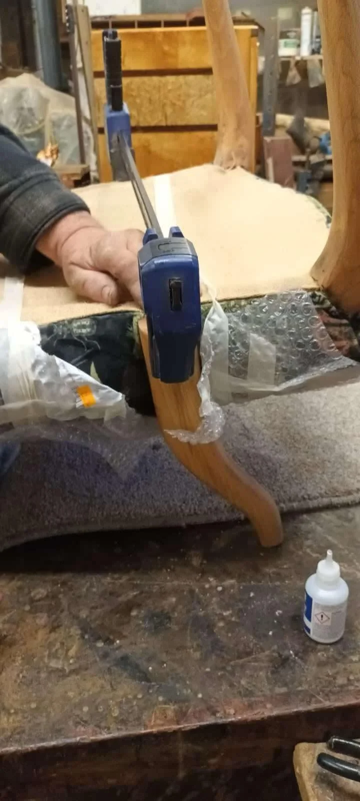Professional chair restoration showing precision clamping of a curved wooden leg - Foxborough Furniture Kent