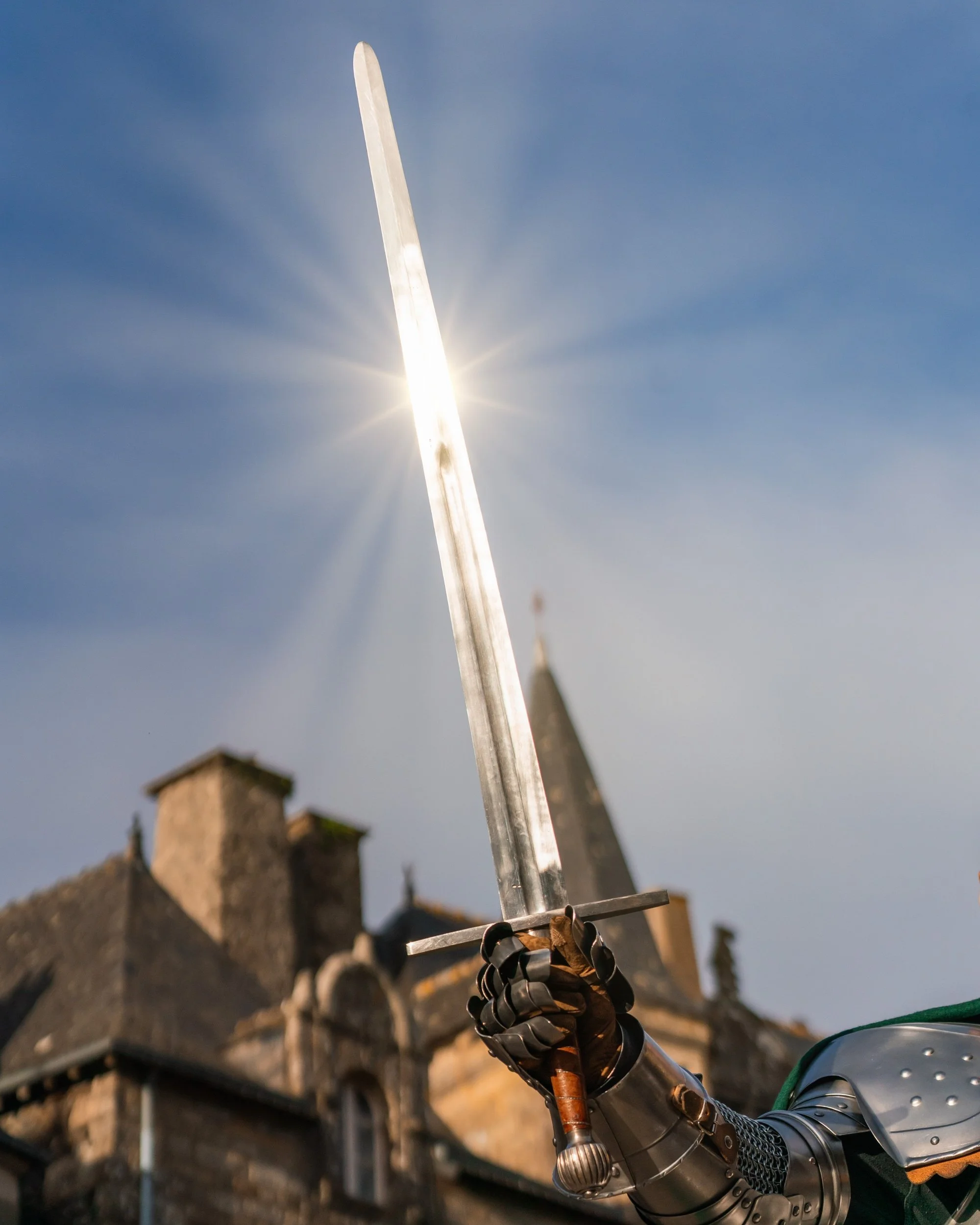 Chevalier en armure brandissant une épée médiévale qui reflète vivement la lumière du soleil