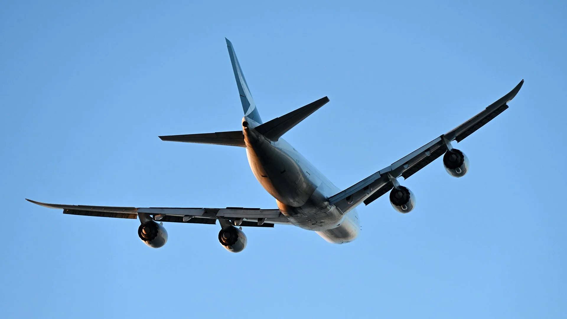 A large commercial airplane flying in the sky taken from below.