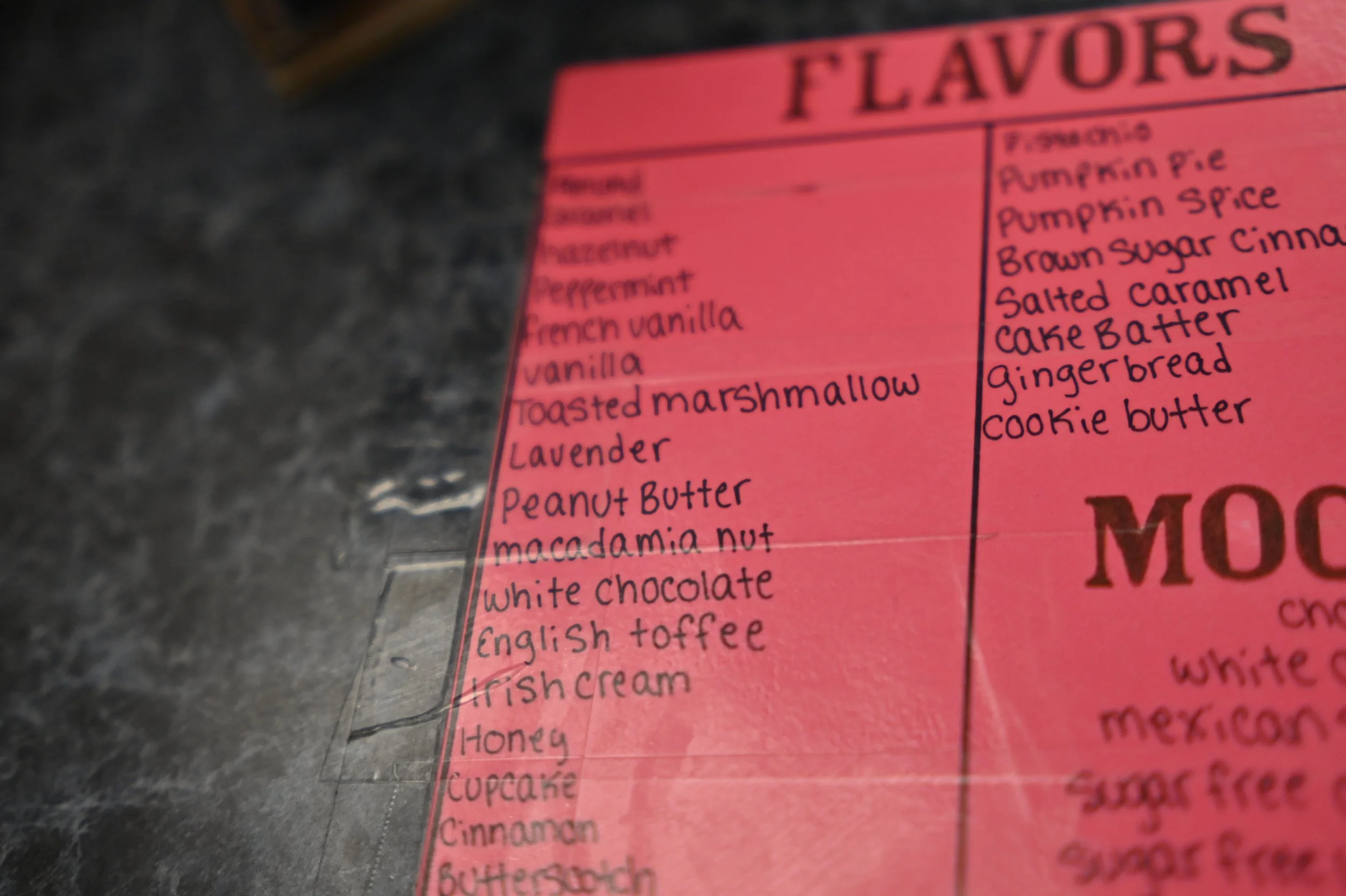 Close-up of a pink menu listing flavors including pumpkin, cinnamon, salted caramel, cake batter, gingerbread, cookie butter, and others.