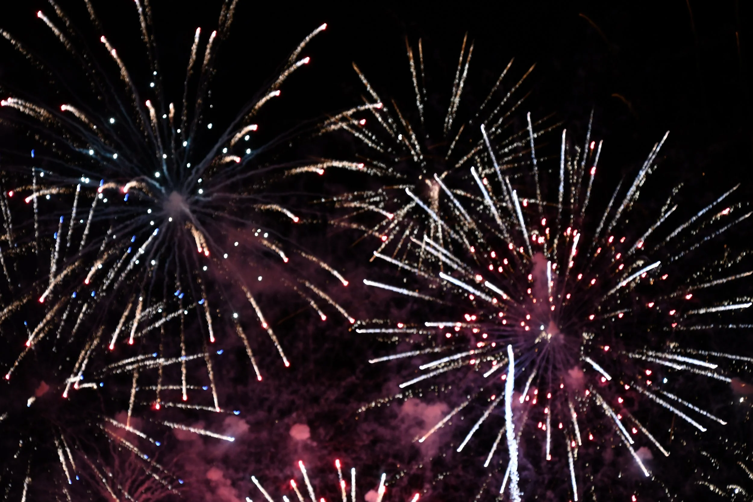 Fireworks exploding in the night sky with various colors and patterns.