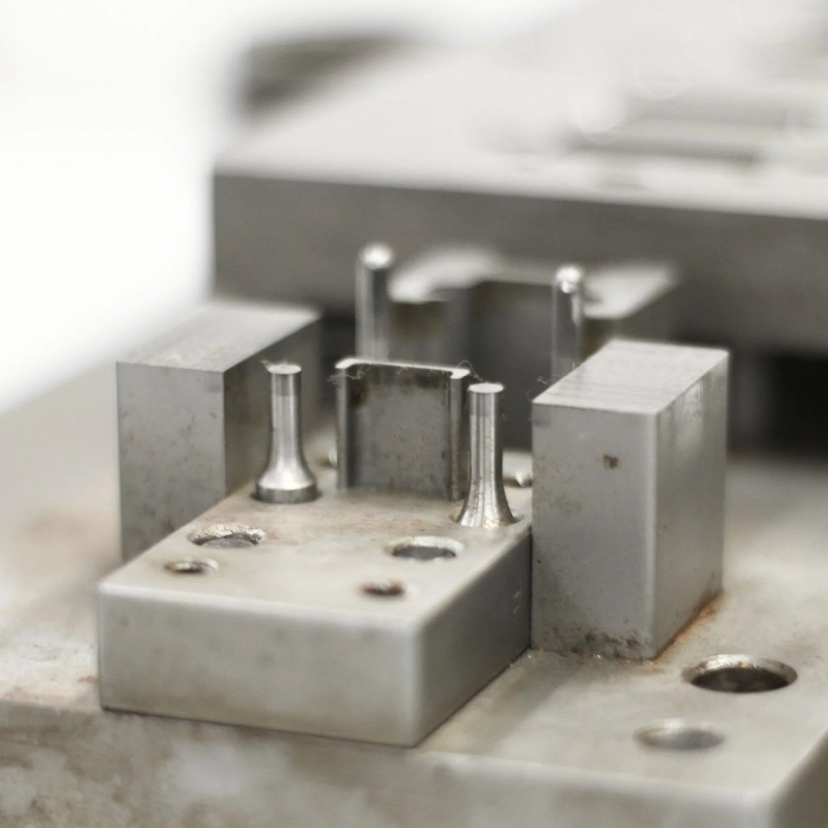 Close-up of a metal mechanical component with pins and holes, possibly part of a precision instrument or machinery.