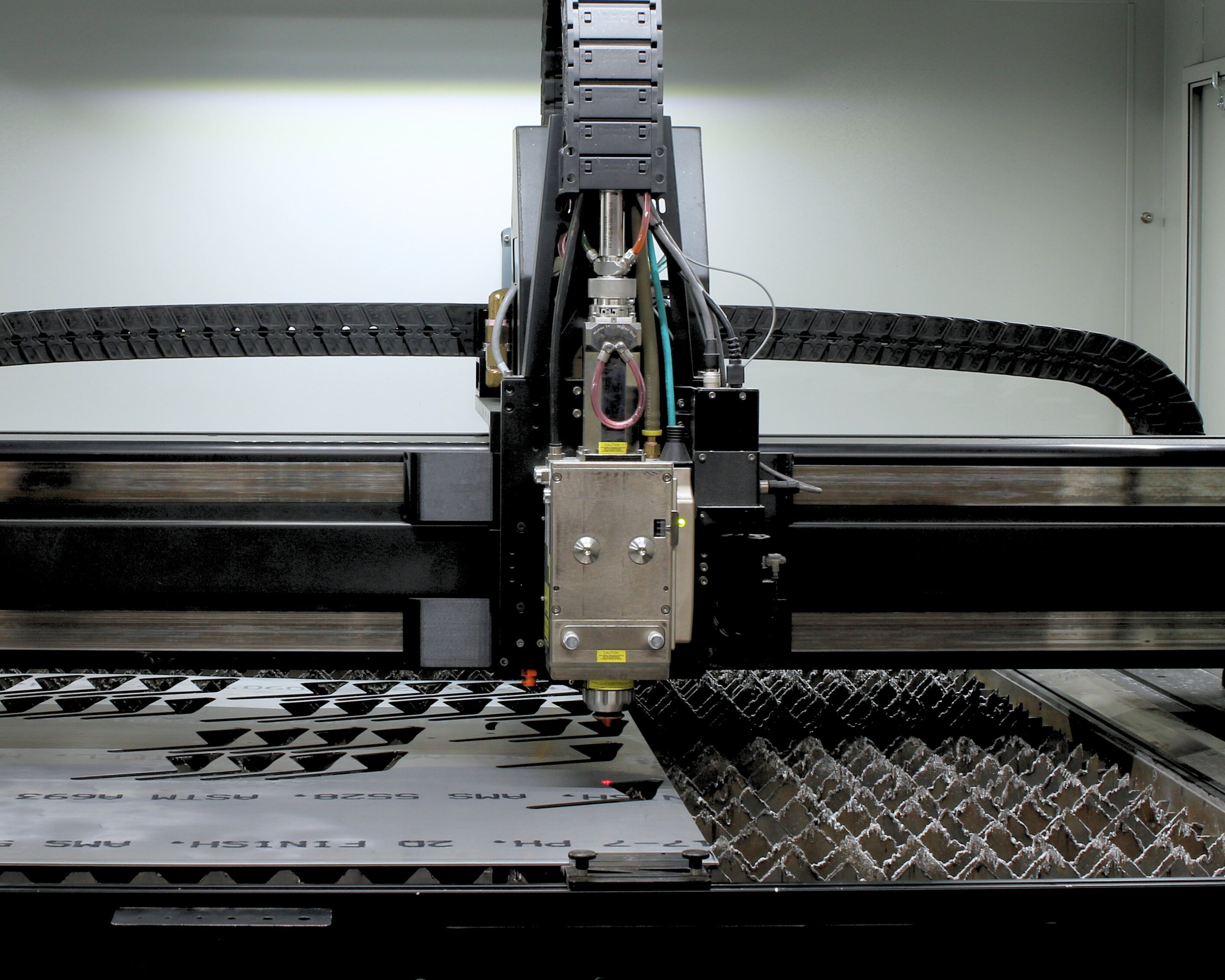 Close-up of an industrial laser cutting machine cutting intricate geometric patterns from a sheet of metal.