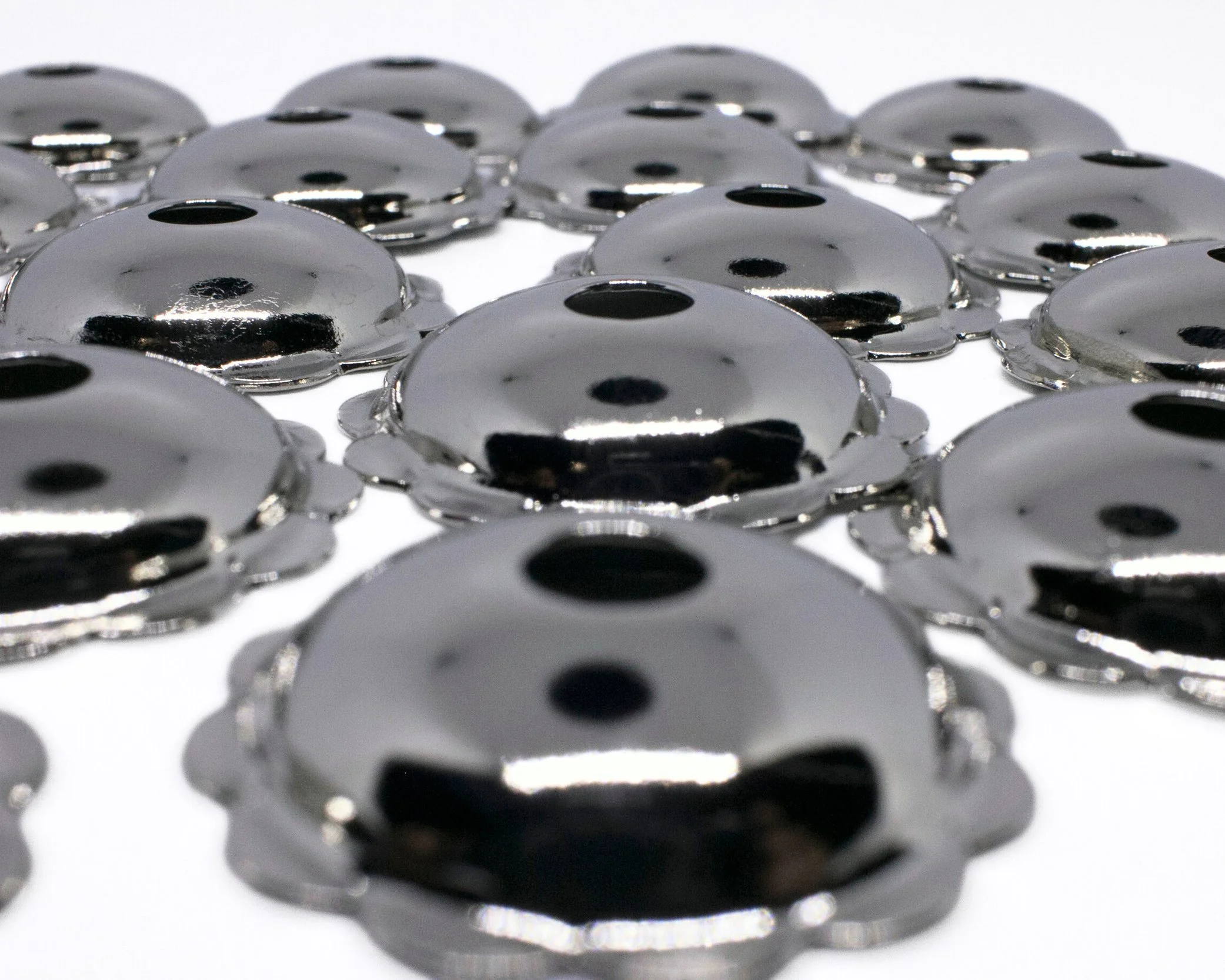 Close-up of shiny, black, circular metal wheels arranged in a grid pattern on a white surface.