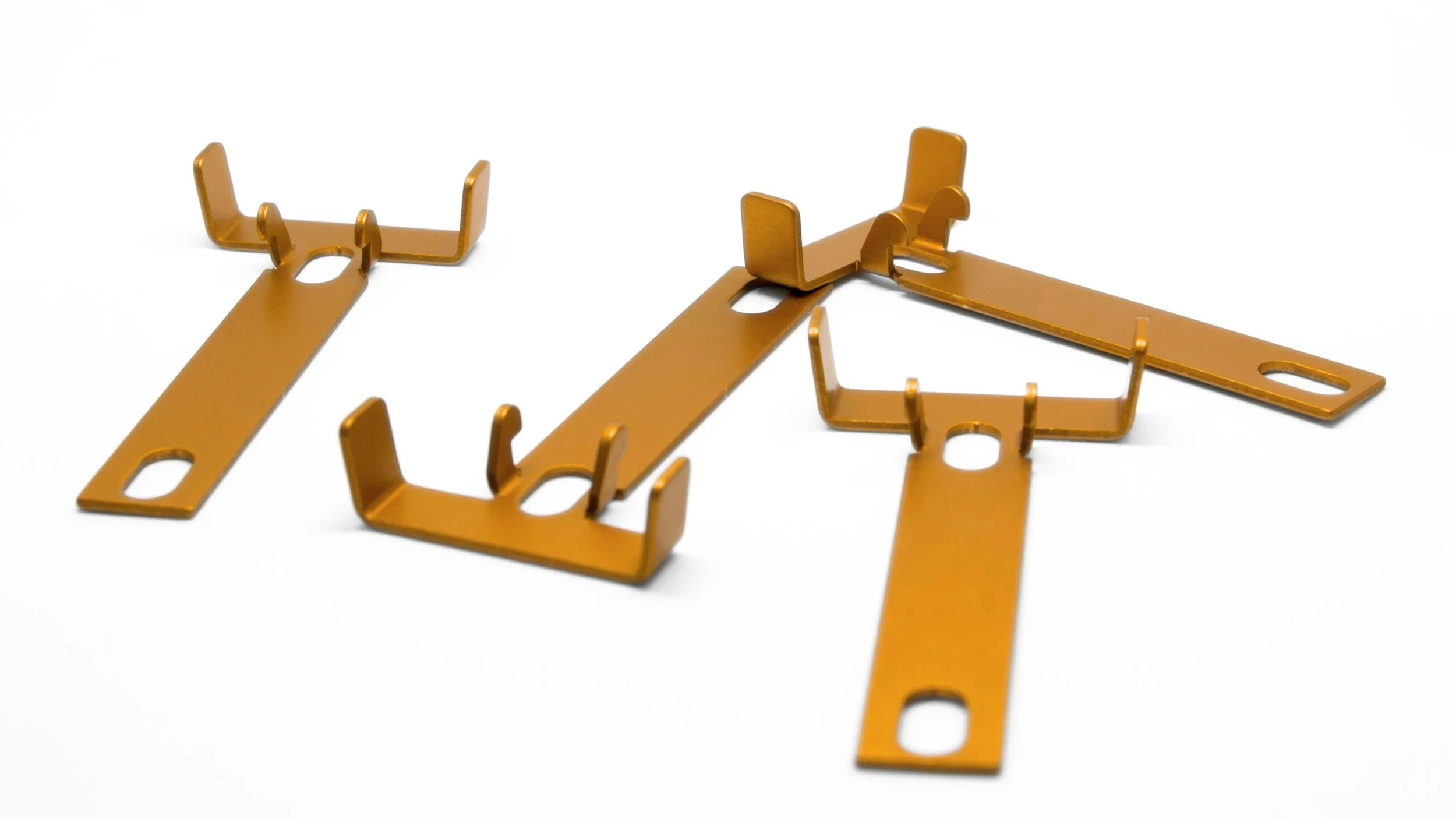 Three orange metal brackets with hooks and elongated holes on flat plates, arranged on a white background.