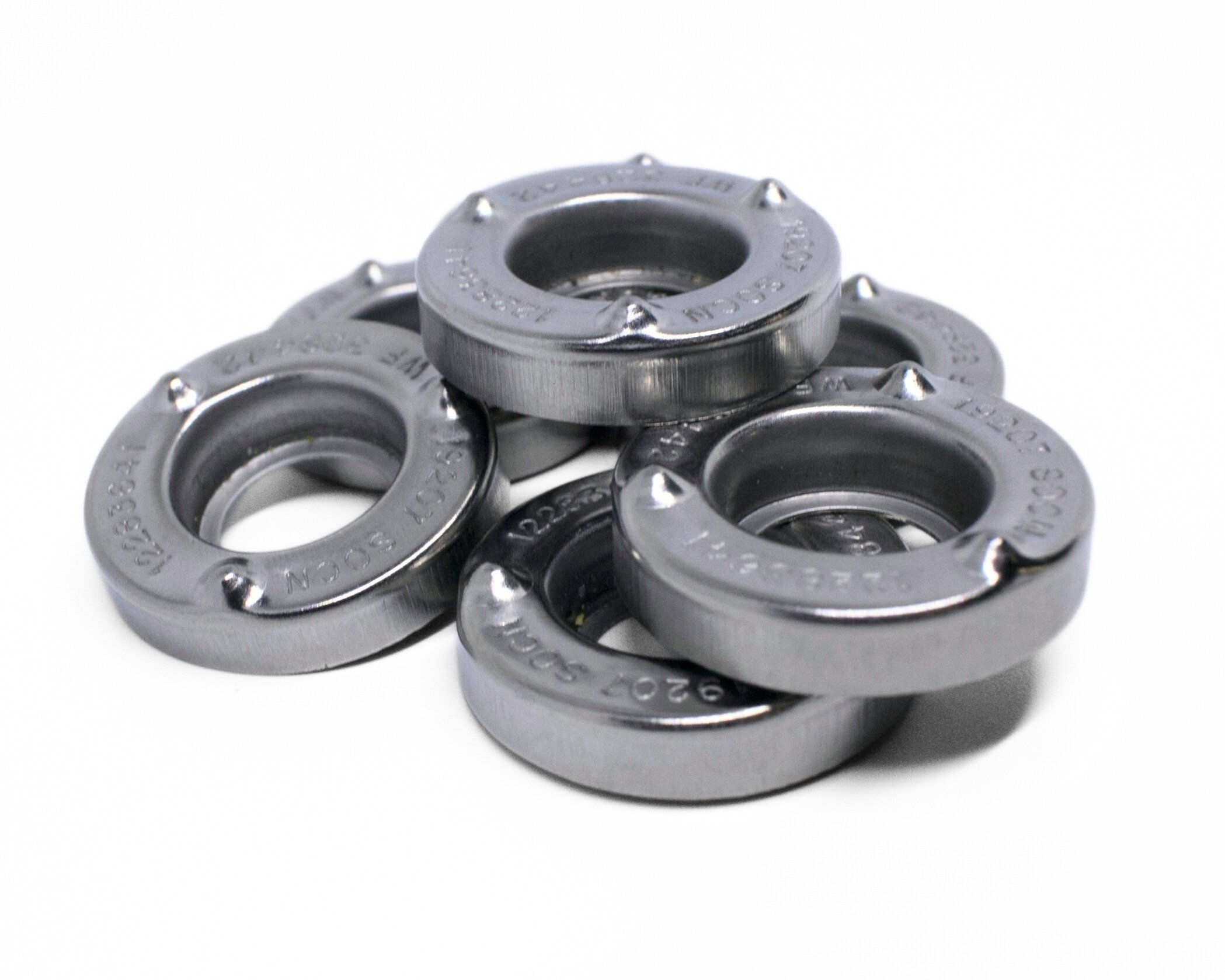 Set of five metal rolling bearings arranged on a white surface.