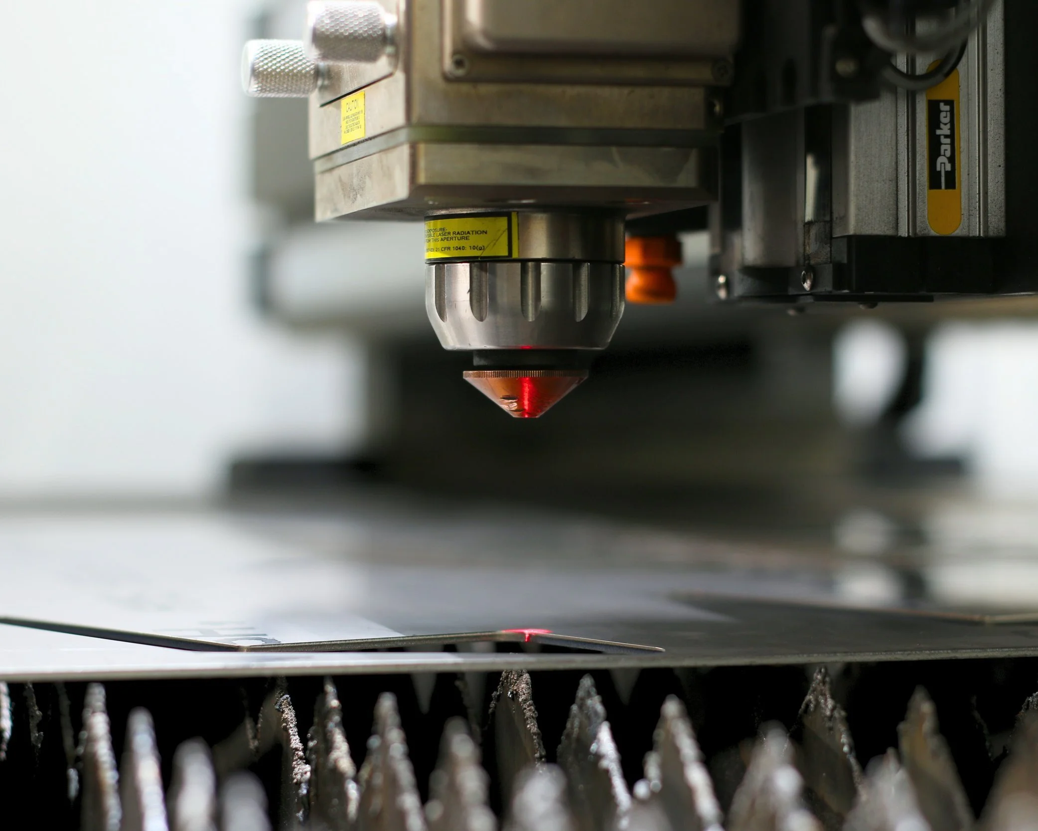 Close-up of a laser metal cutting machine with a red laser focused on a sheet of metal, preparing to cut.
