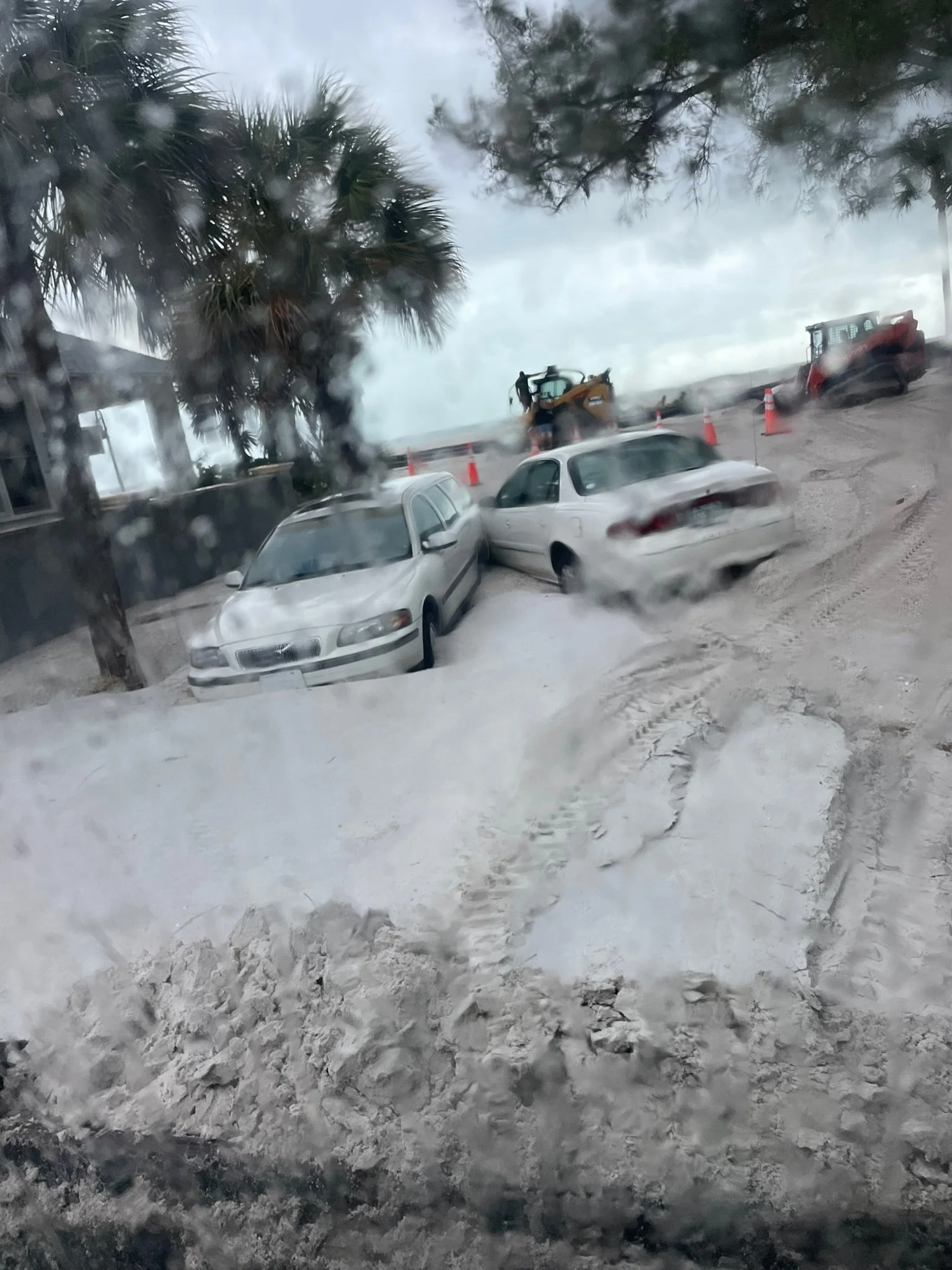 Frozen cars on a snow-covered street during a snowstorm or blizzard, with heavy snow accumulation and visibility reduced.