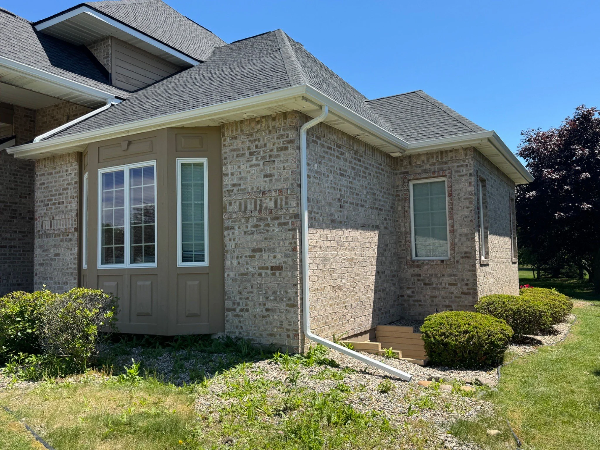 New gutters and downspout installed along the side of a brick home in Saginaw Township, MI