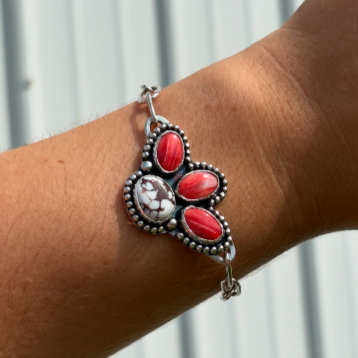 Silver bracelet with red and white gemstone beads on a person's wrist.