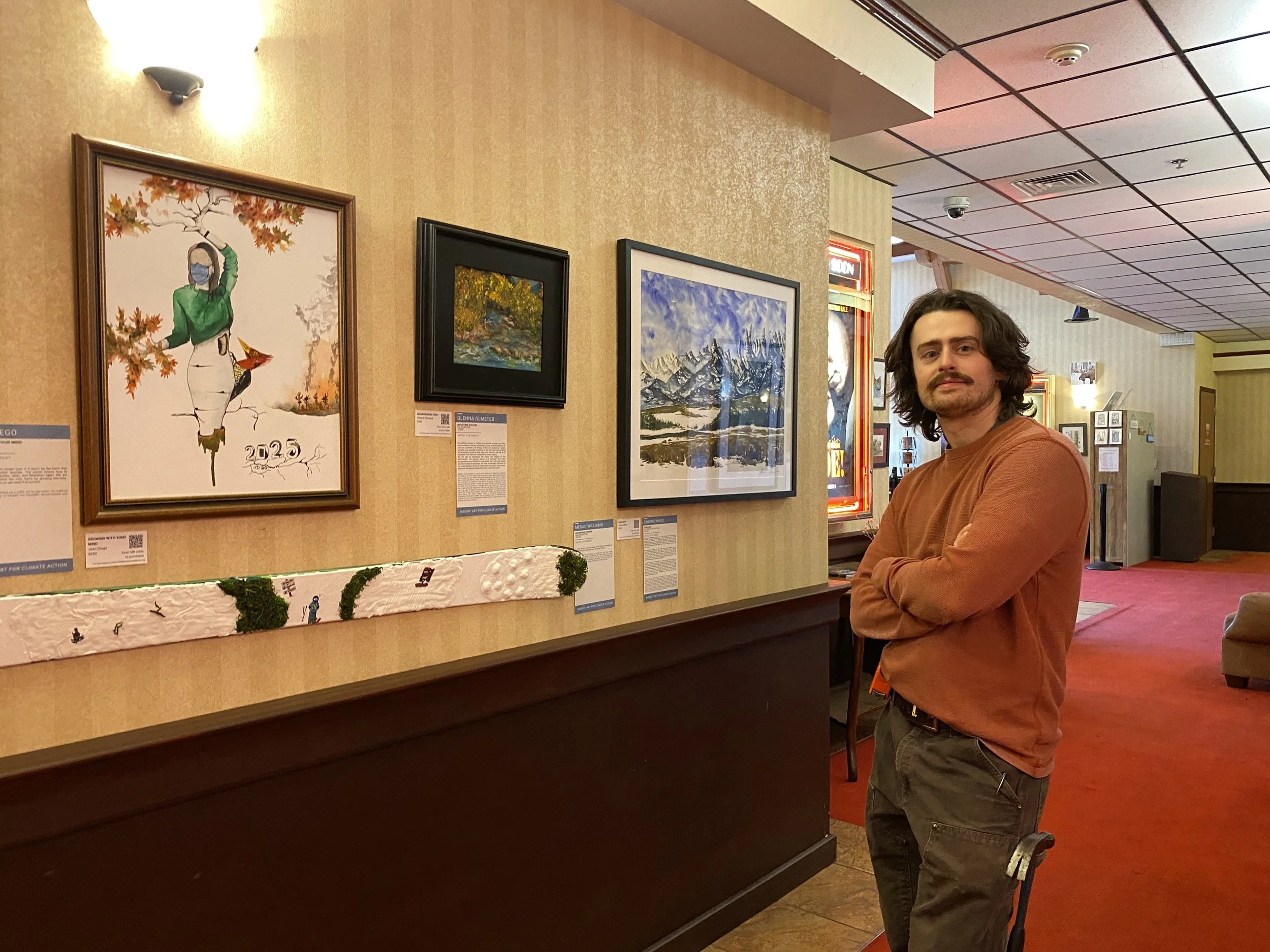 Silas Axtell hanging art for Insight: Art for Climate Action