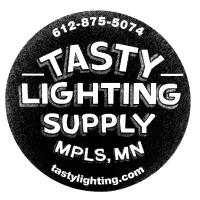 Close-up of a black coin or token with embossed text reading 'Tasty Lighting Supply, Minneapolis, MN'.