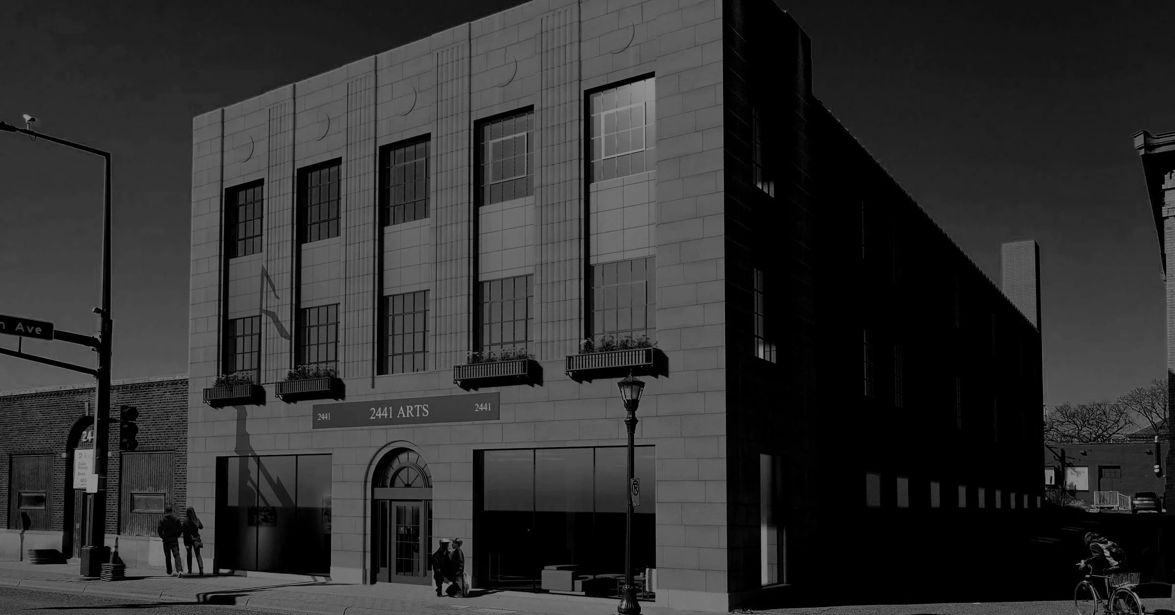 A modern building with a sign that reads '2441 Arts' on the front, featuring tall windows, balconies with plants, and a sidewalk with pedestrians and street lamps.