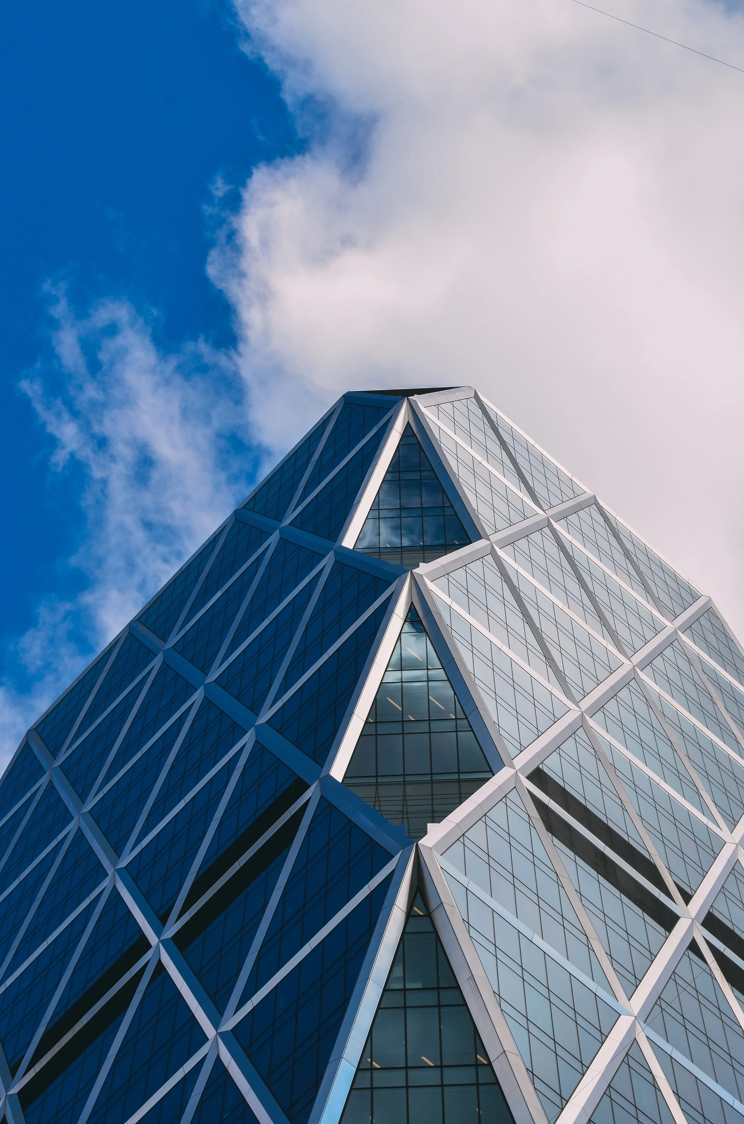 Modern skyscraper with a glass exterior and geometric pattern, set against a partly cloudy sky.