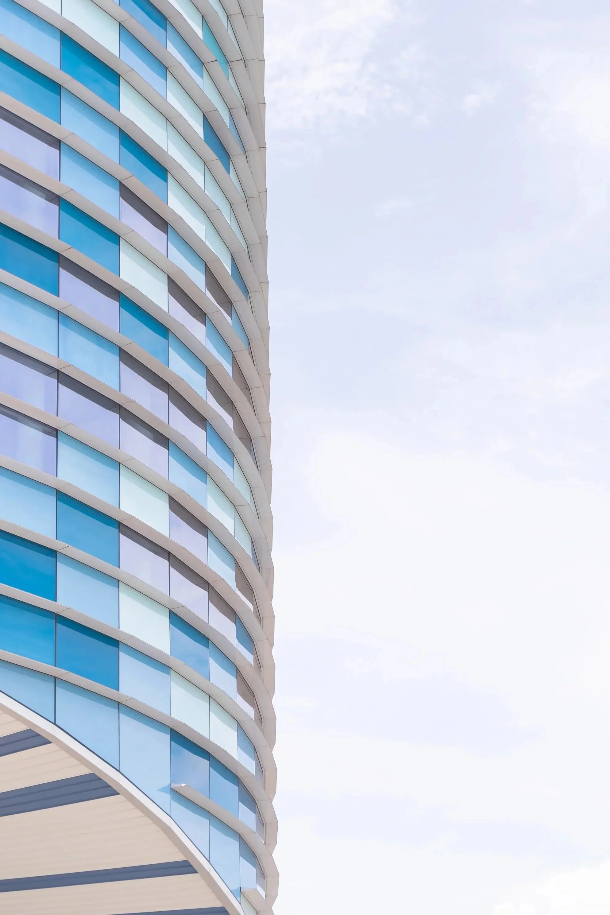 A modern building with curved glass windows reflecting the sky.
