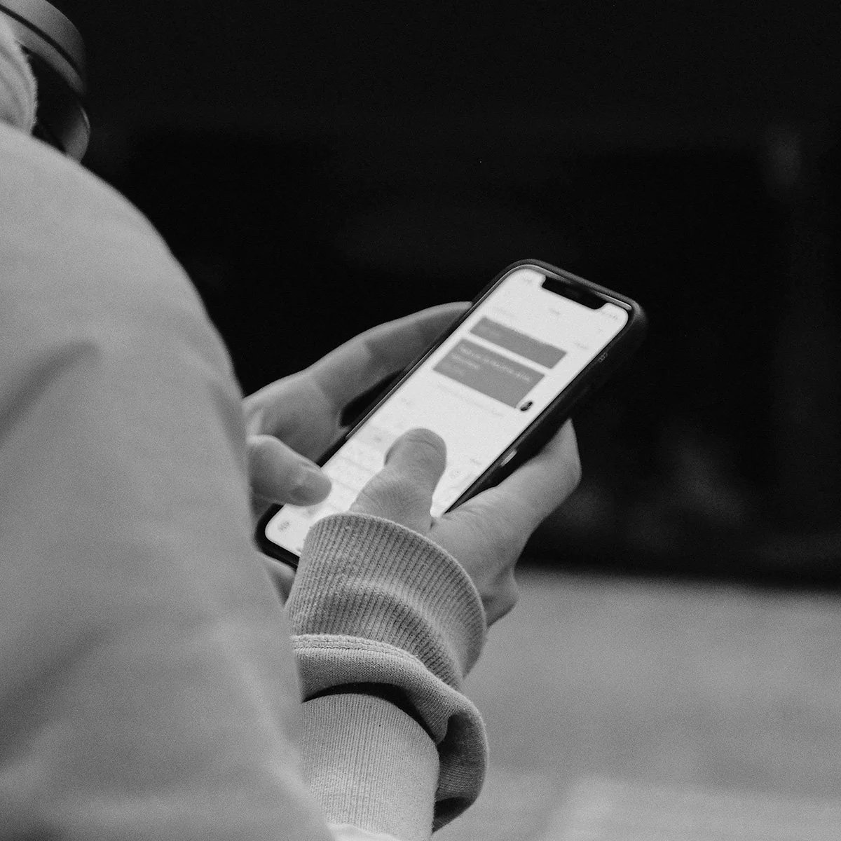 Person holding and using a smartphone, scrolling or reading messages in a dark environment