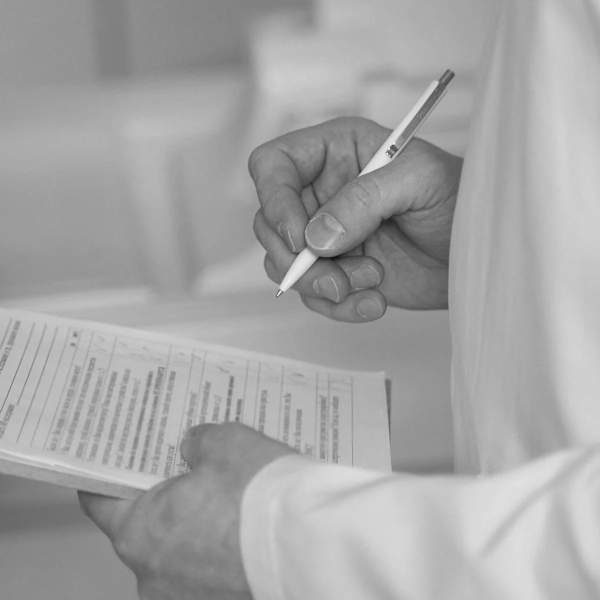 A person holding a document with both hands, writing on it with a pen.