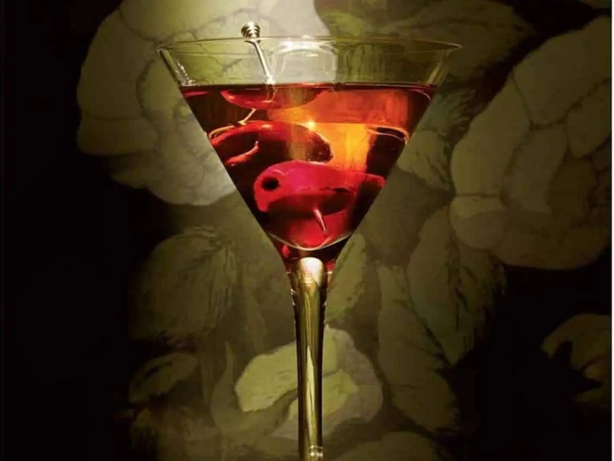 A cocktail glass filled with a red-colored drink garnished with cherries, set against a dark background with subtle floral patterns.