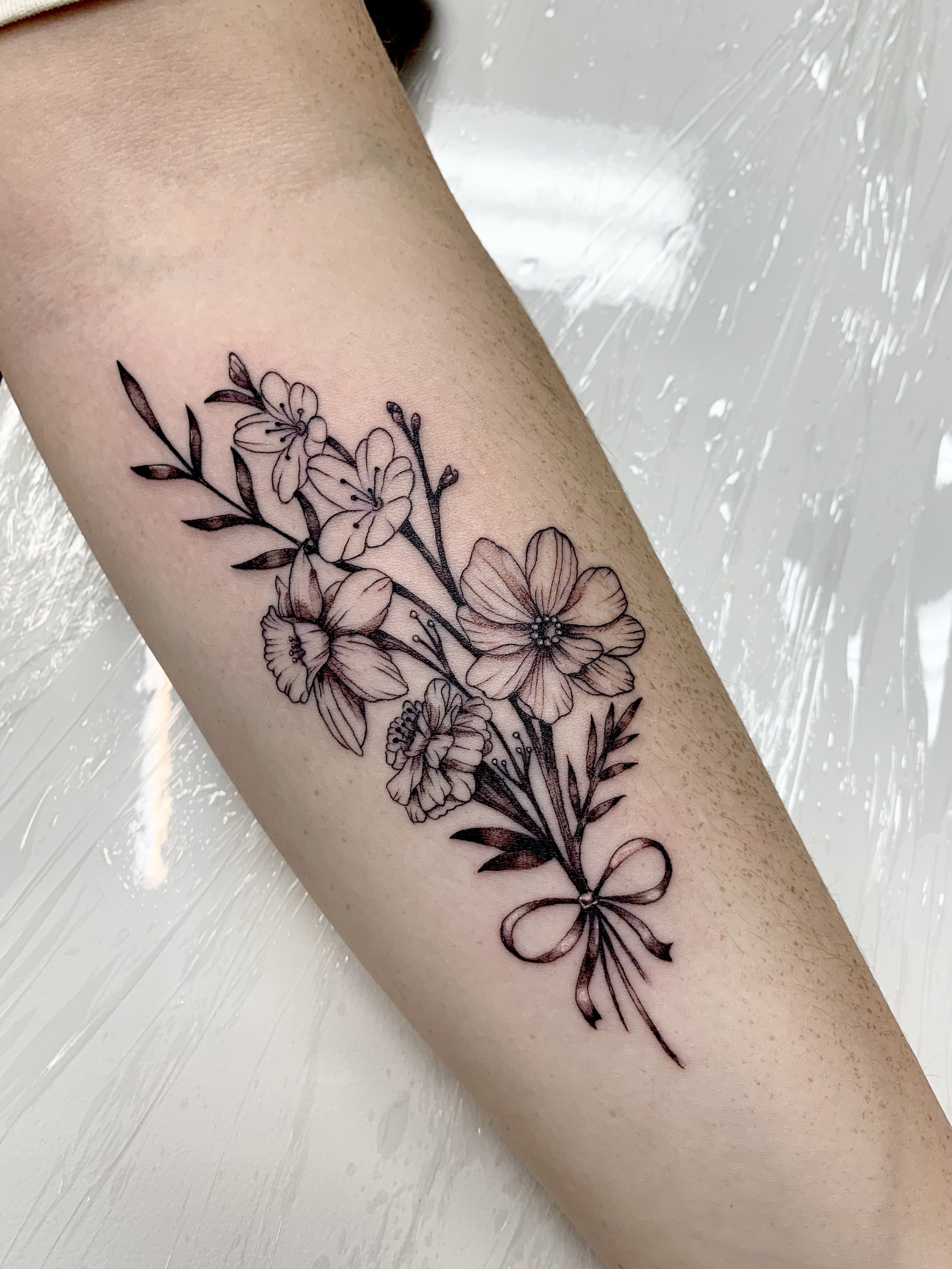 Fine line flower bouquet with ribbon tattoo