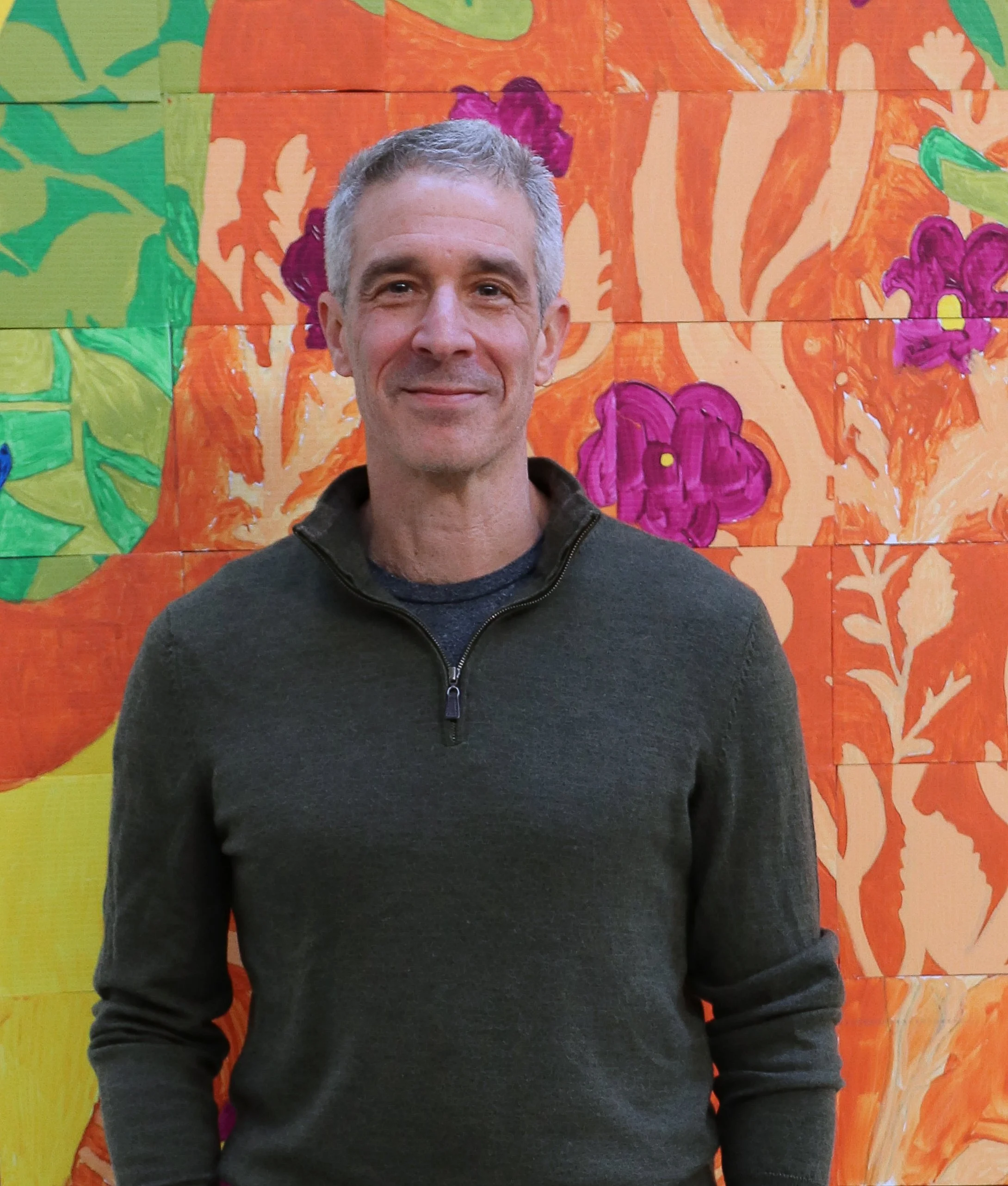Sanford Hess stands in front of a painted picture of flowers.