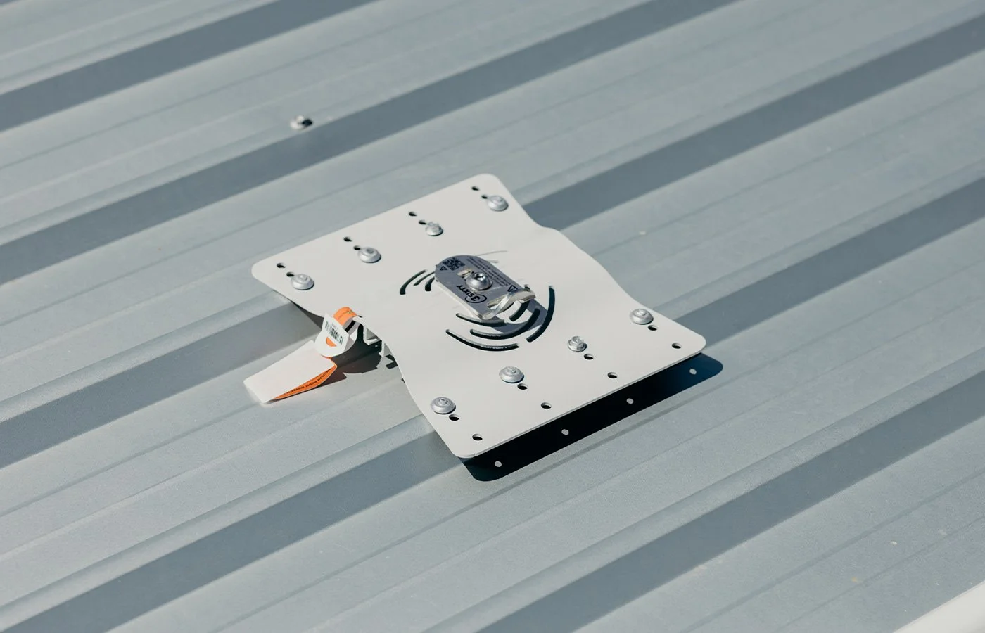 Close-up of metal bracket with bolt and circular hole underneath, attached to a flat surface, showing Roof Anchor Installations and Certifications