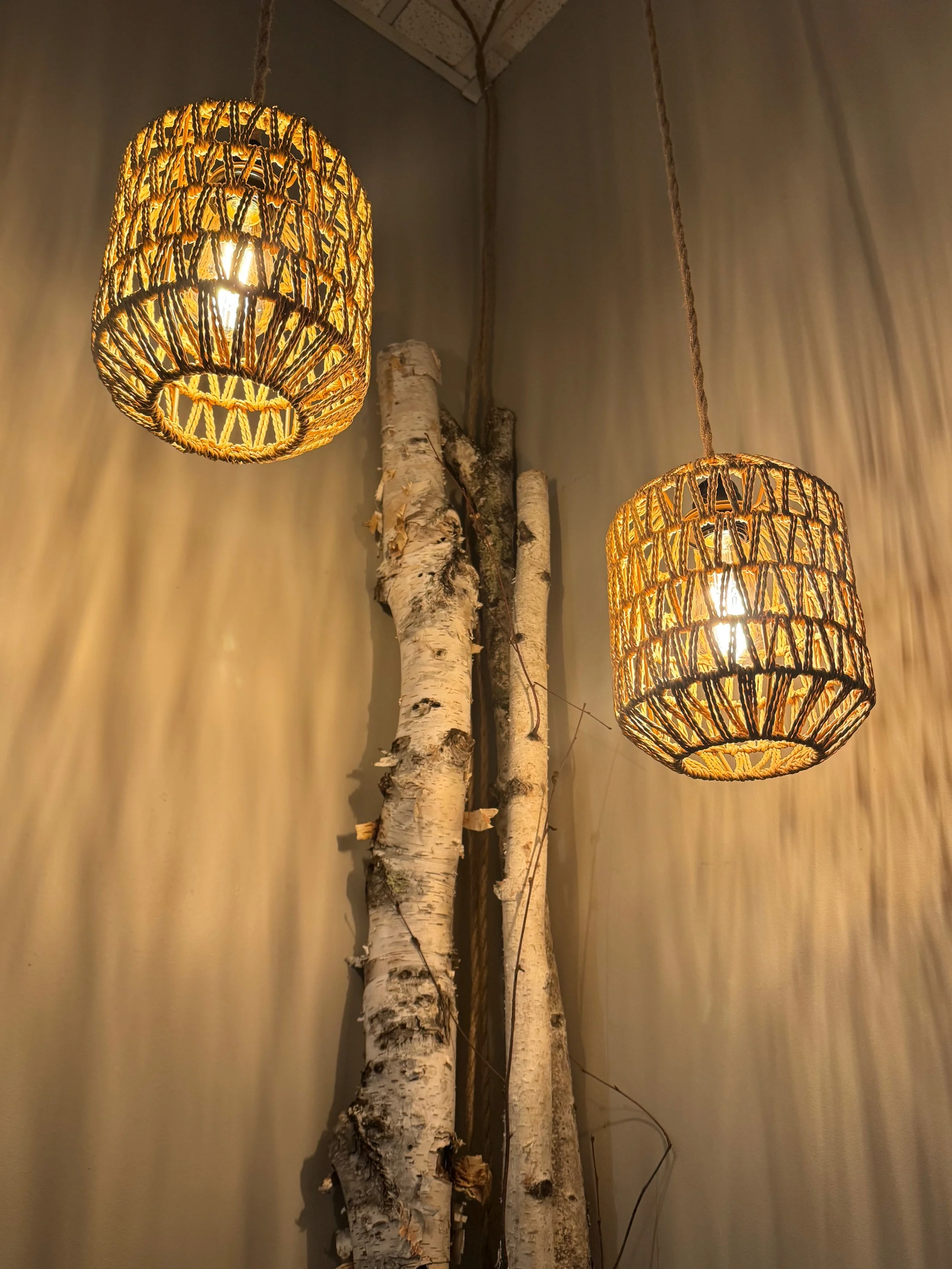 Two woven pendant lights hanging from the ceiling, with a decorative piece resembling tree branches behind them.