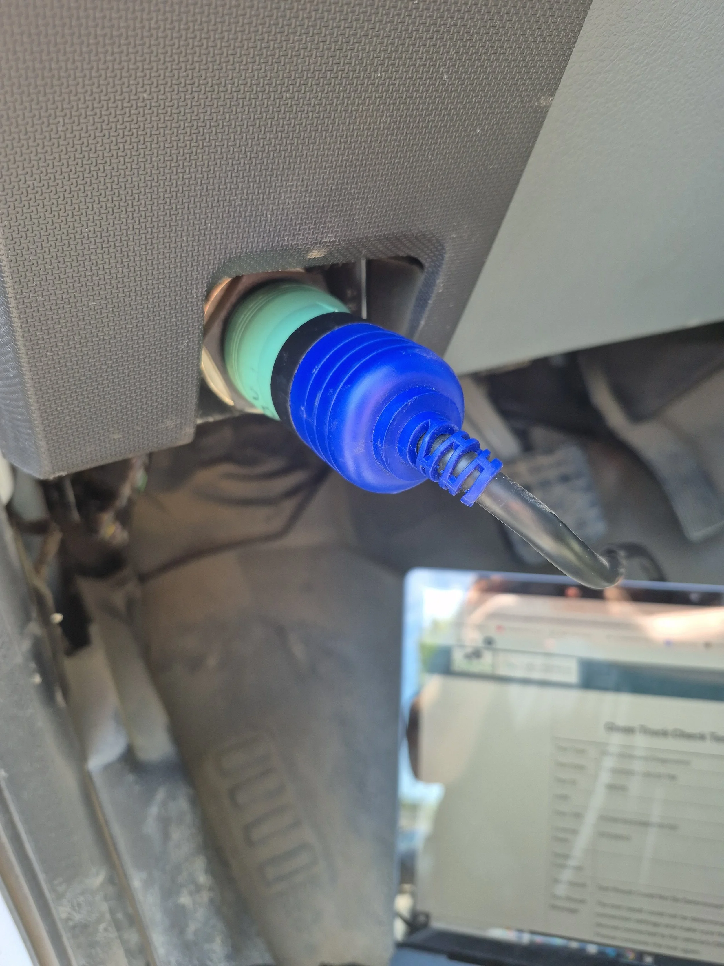 Close-up of a control switch with a blue rubber cover and a coiled cord, attached to a vehicle dashboard.