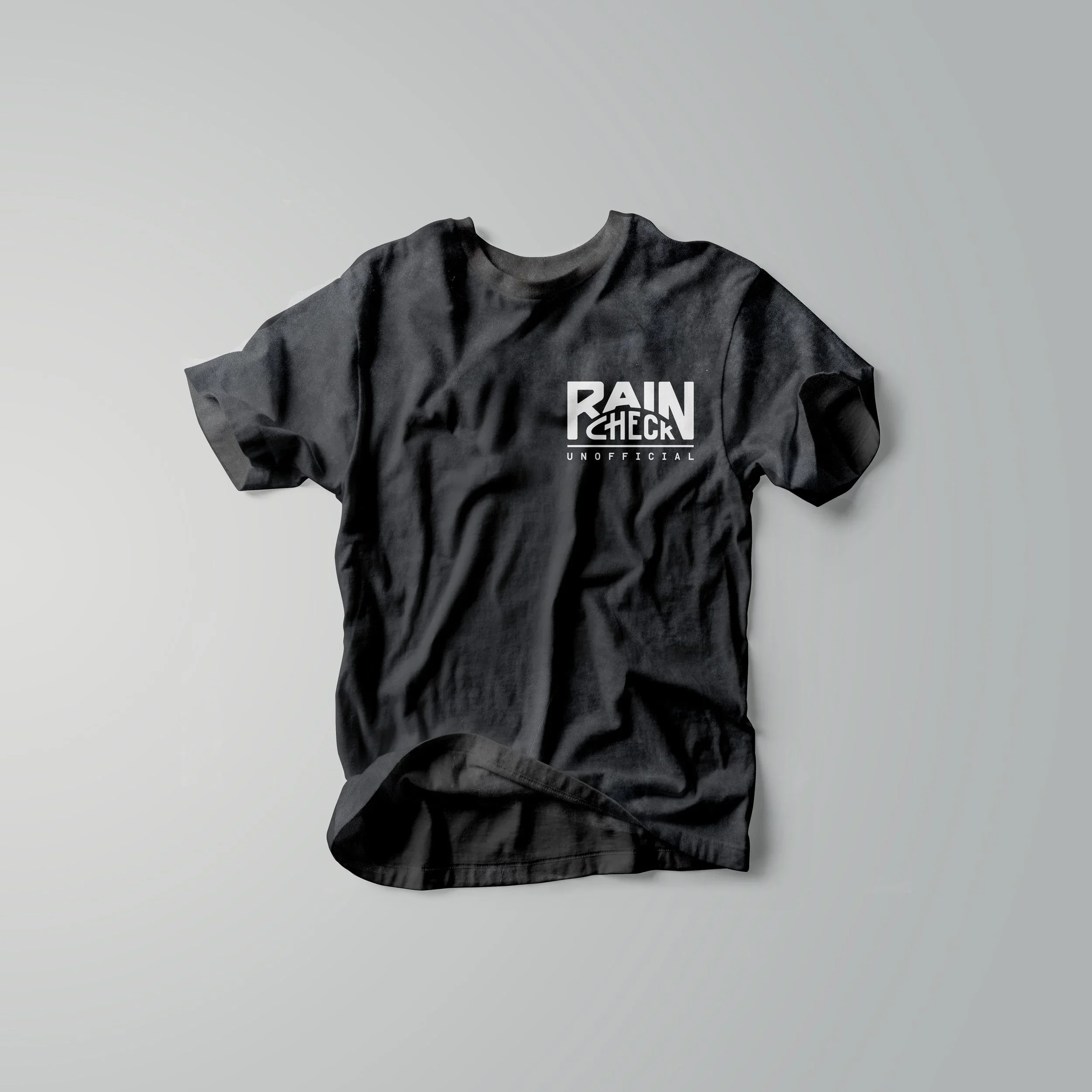 Black RAINCHECK “Unofficial” t-shirt featuring minimalist sports-inspired branding and modern Americana streetwear design.