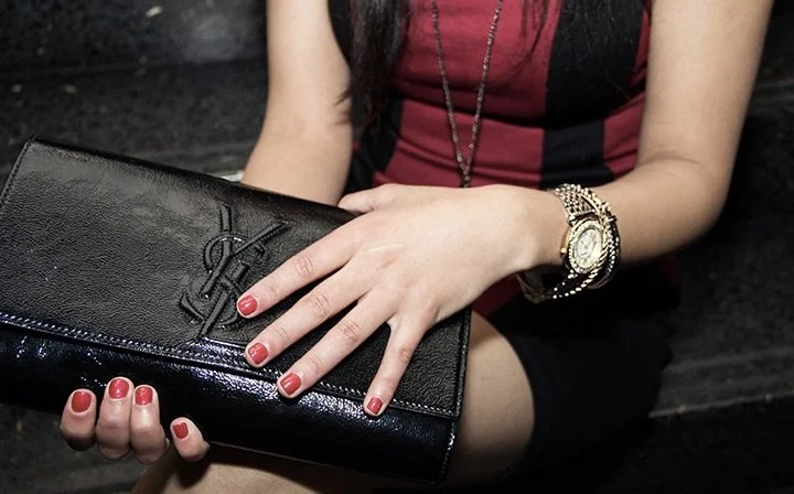 Close-up of luxury fashion styling with black clutch and red manicure for SPANISHROSE editorial.