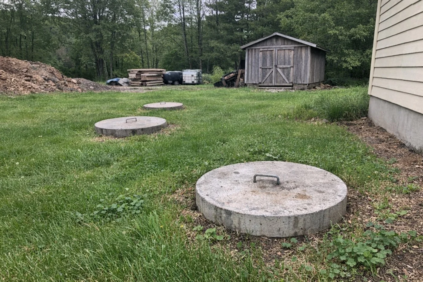 Septic tank access lids in the lawn behind a country house
