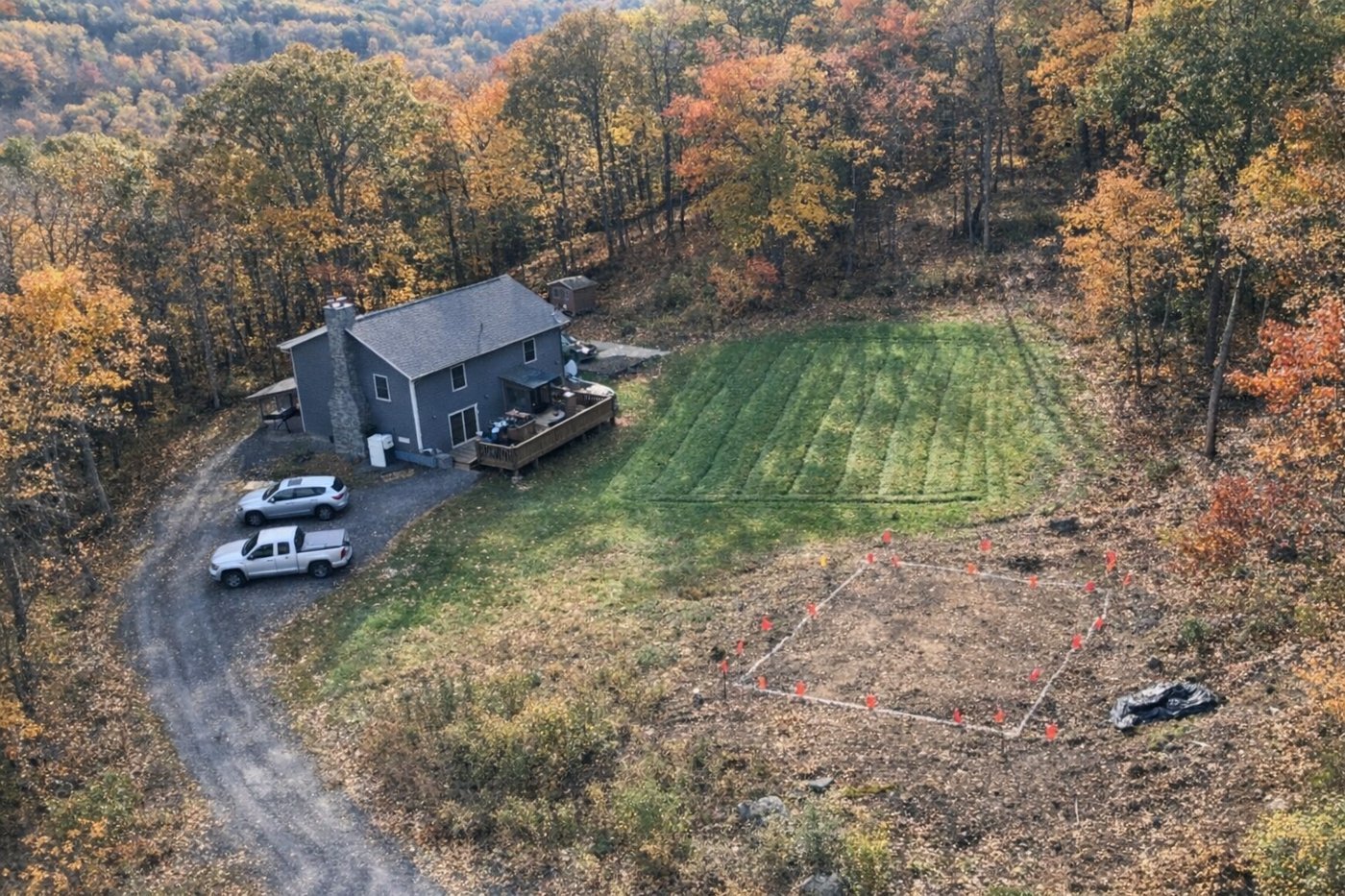 Aerial view of a sloped rural lot with flags marking an addition