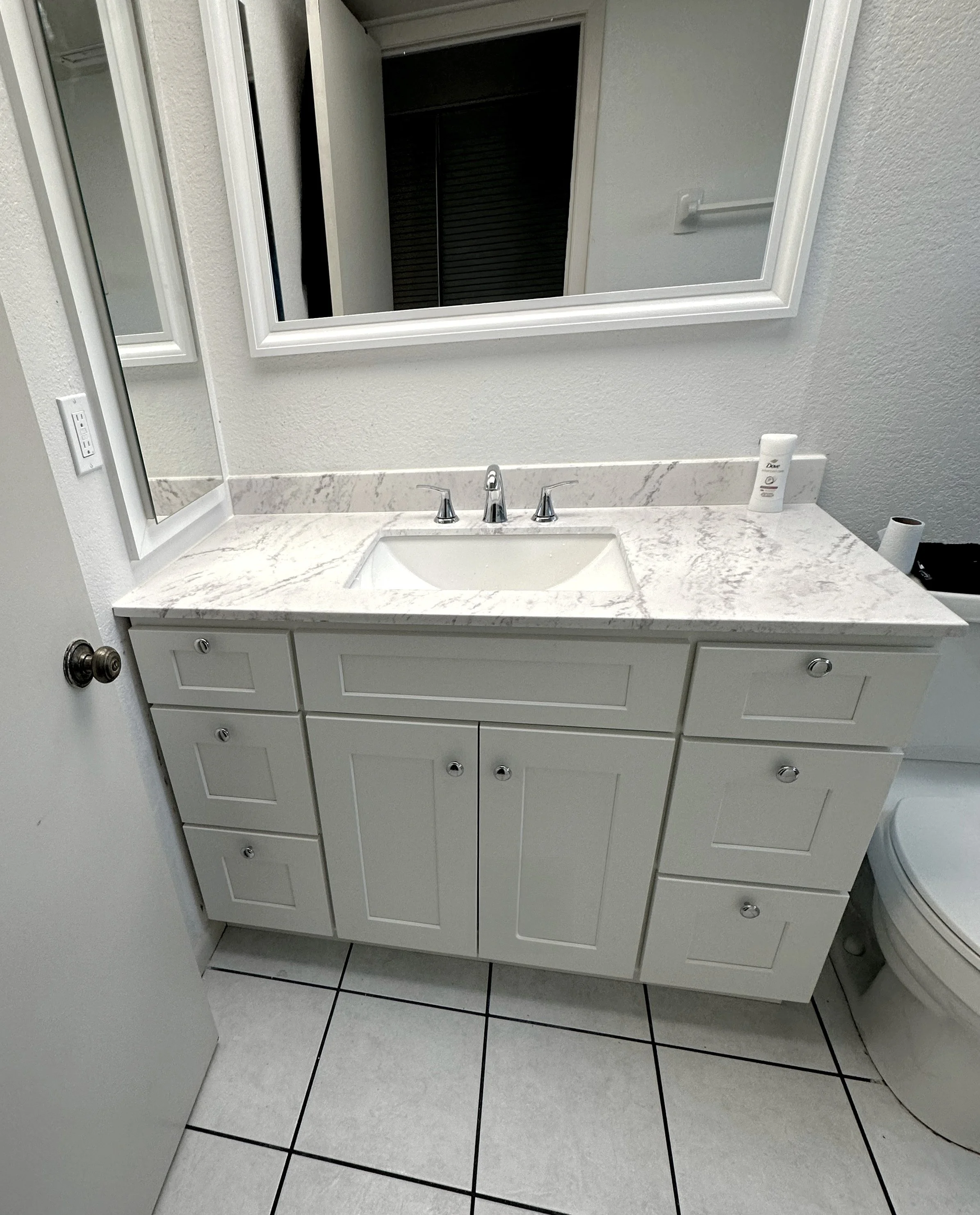A custom bathroom vanity with a white cabinet and a marble countertop.