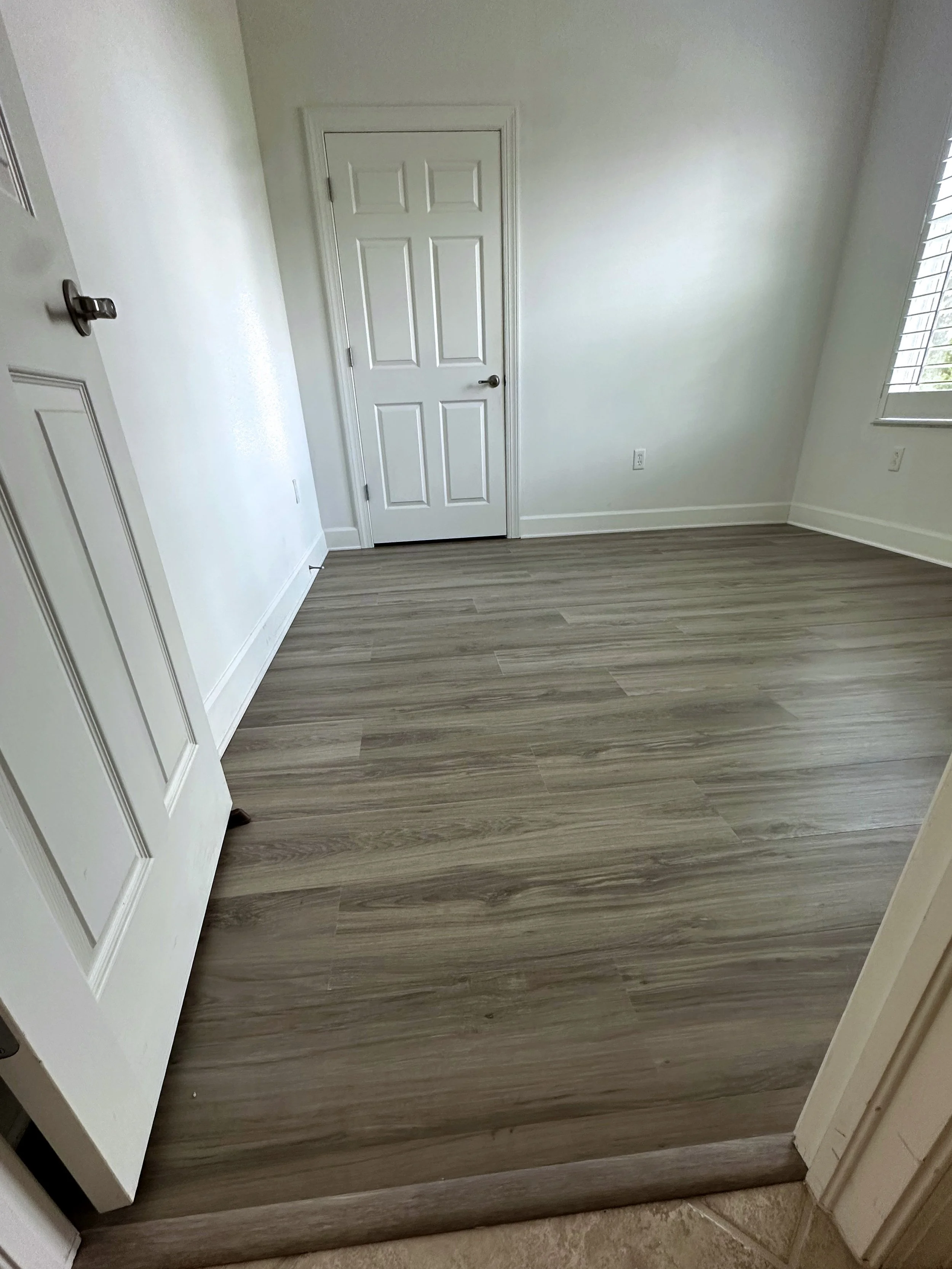 Freshly installed vinyl flooring and trim in a bedroom.