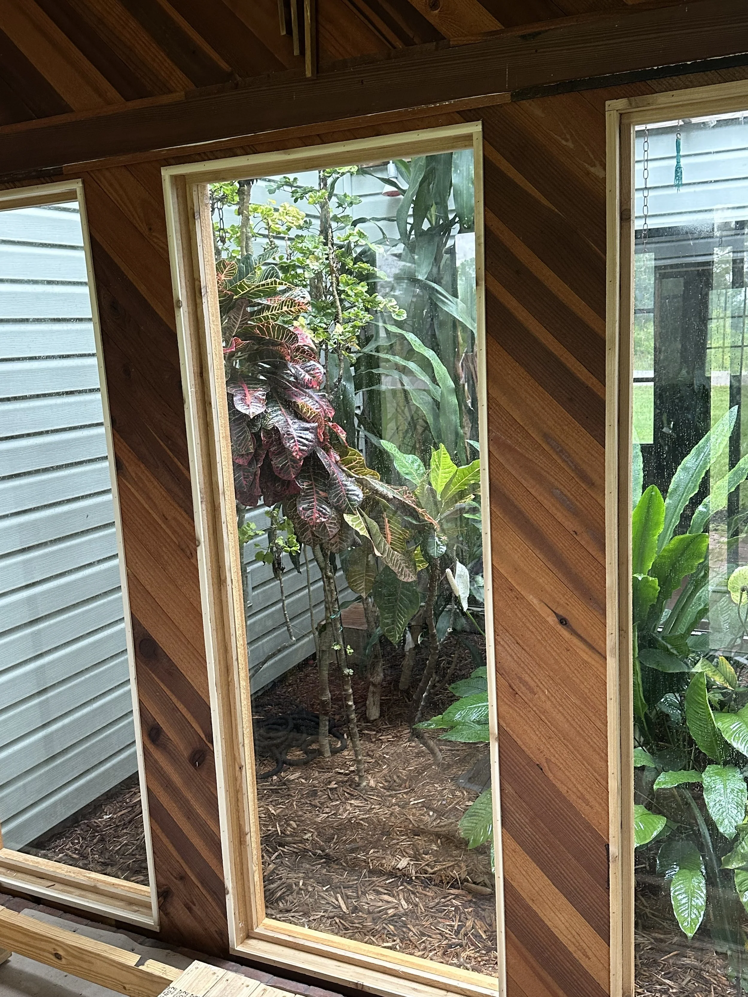 View of a newly installed, custom cut glass atrium, framed and finished with wood paneling.