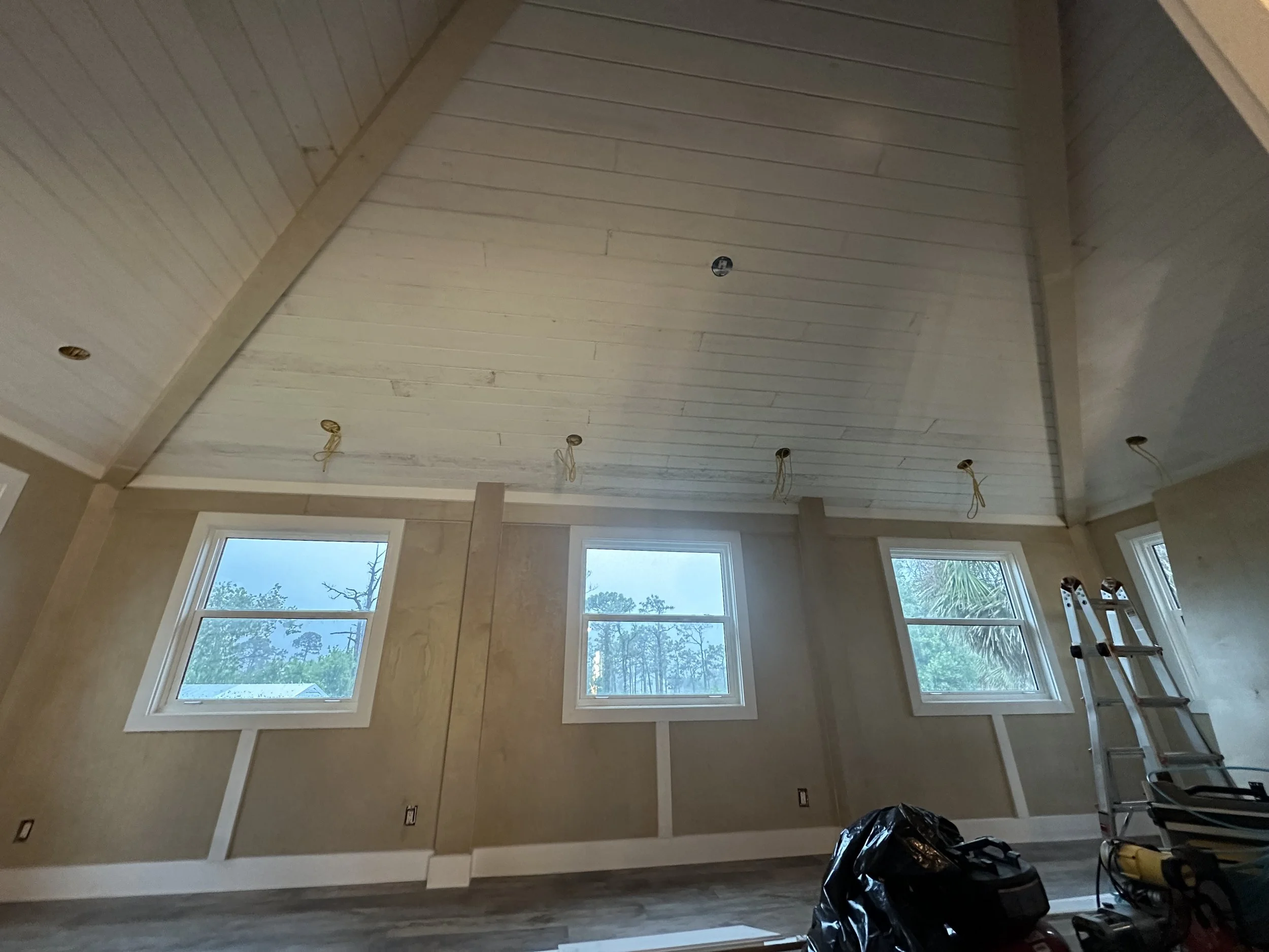 Interior of a room under renovation with a tongue and groove ceiling and custom trim through out.