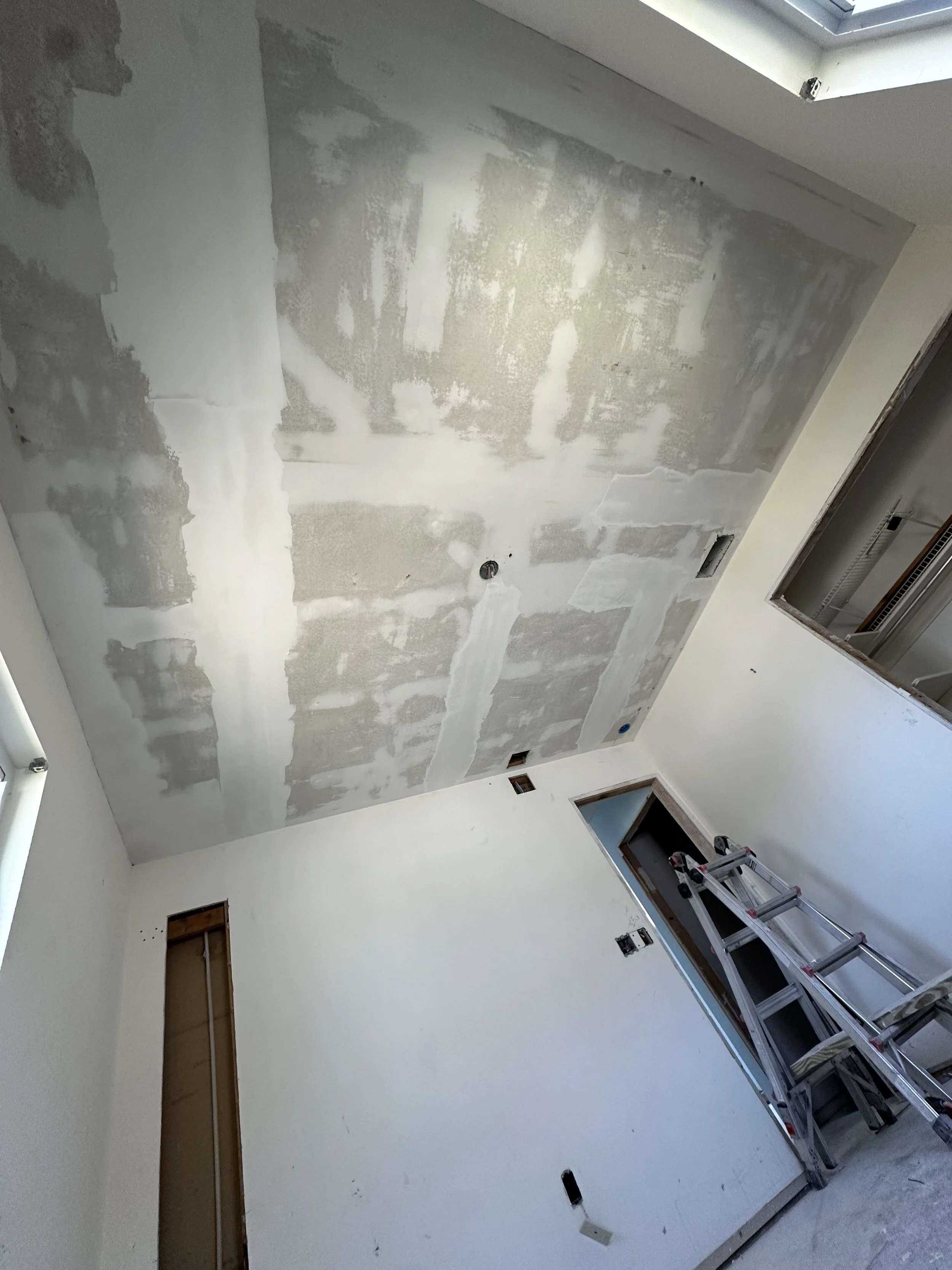 Room under renovation showing drywall ceiling with patches.