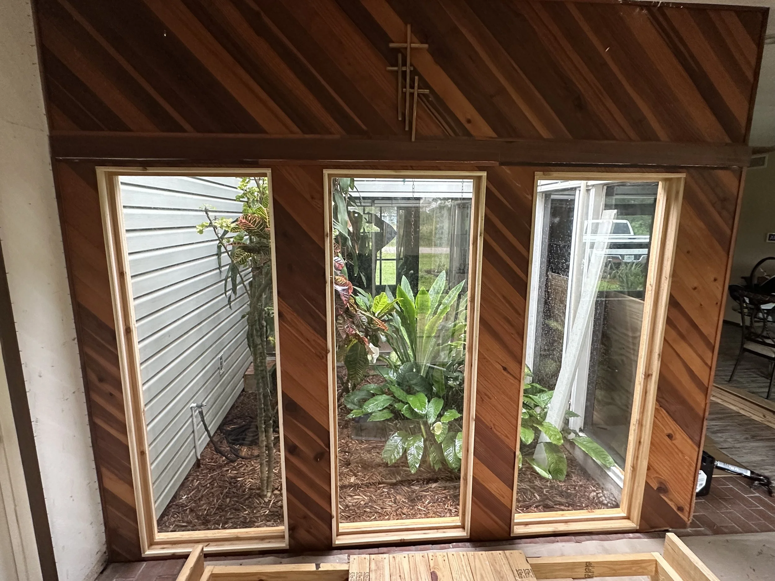 View of a newly installed, custom cut glass atrium, framed and finished with wood paneling.