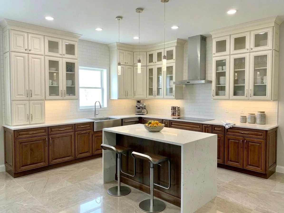 Modern kitchen with white and wooden cabinets, marble island, pendant and recessed lighting, stainless steel appliances, and tiled flooring.