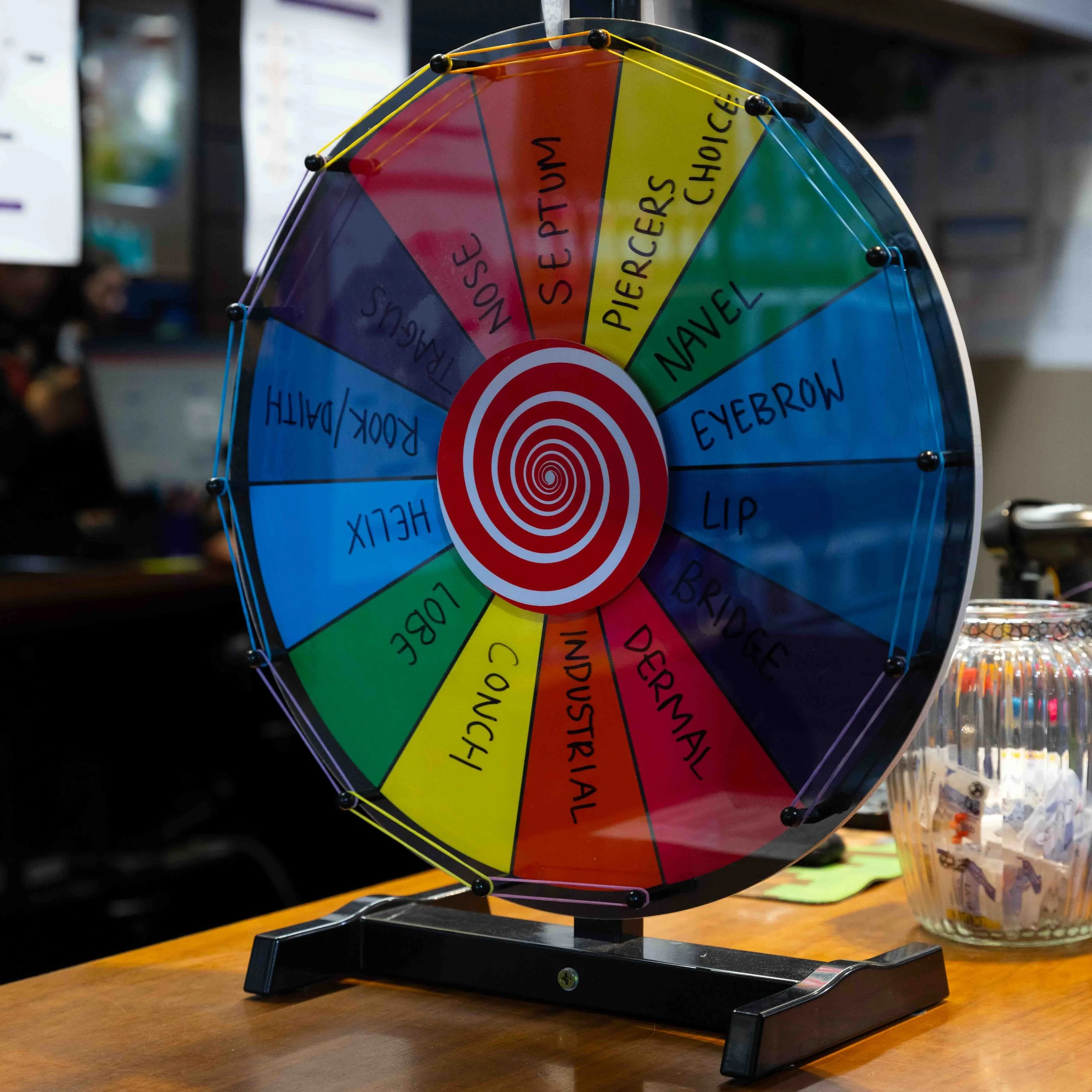 A colorful spinning wheel with labeled sections such as nose, mouth, eyebrows, lips, bridge, eye, cheek, jaw, and chin, used for a game or activity.