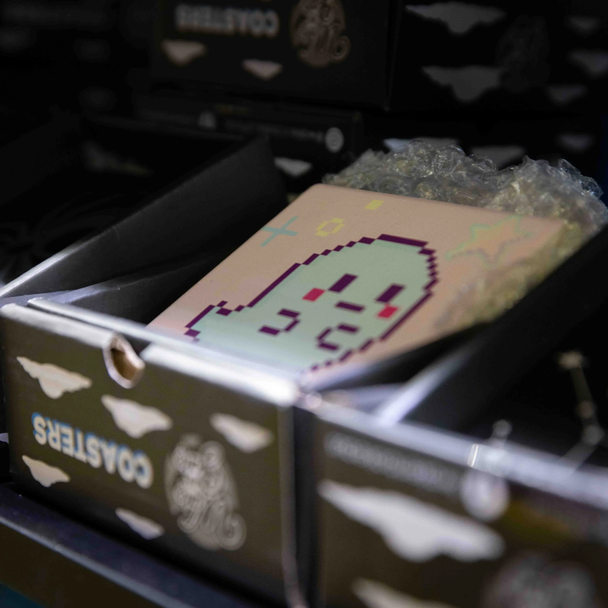 A black box of Cornsticker candies with pixel art of a Ghost character on a pink background inside the box.