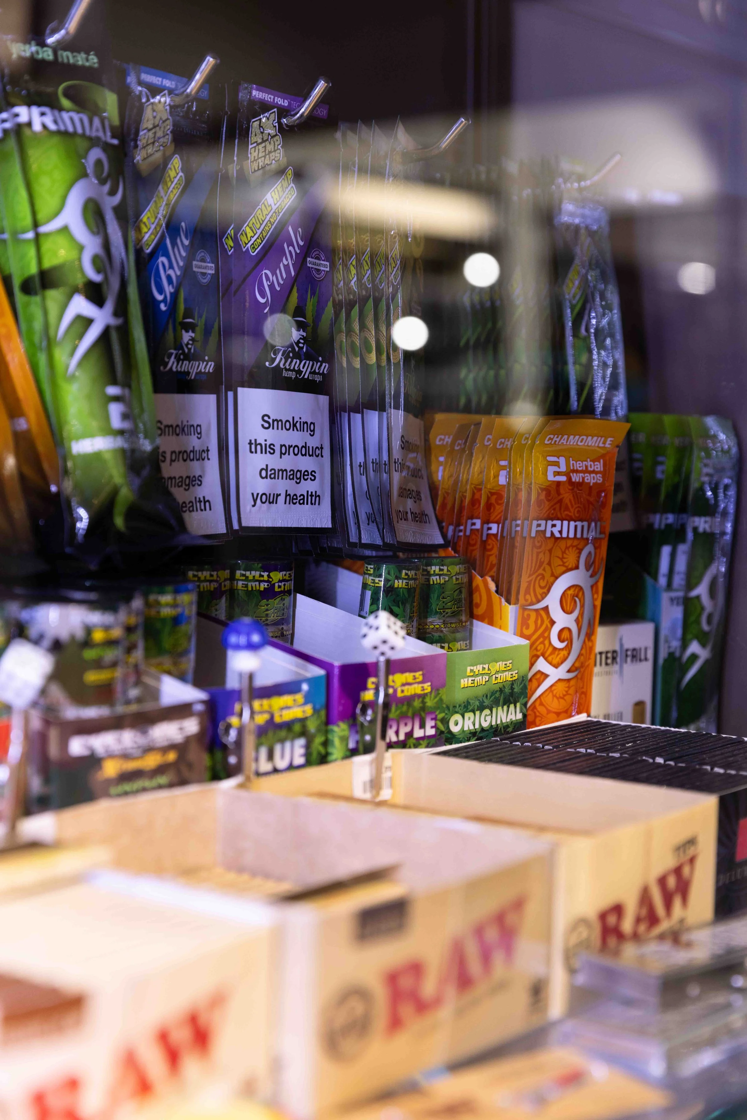Vape products in a vending machine, including packages labeled 'Prime' and 'Herbal Wraps' with various colors and warning labels.